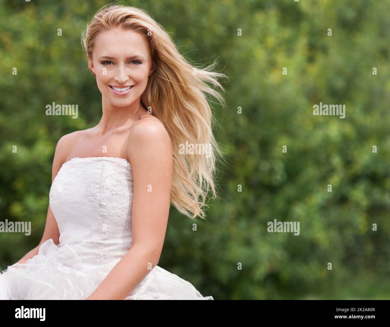 Atemberaubend an ihrem großen Tag. Eine wunderschöne junge Braut lächelt und sieht in ihrem Hochzeitskleid neben Copyspace atemberaubend aus. Stockfoto
