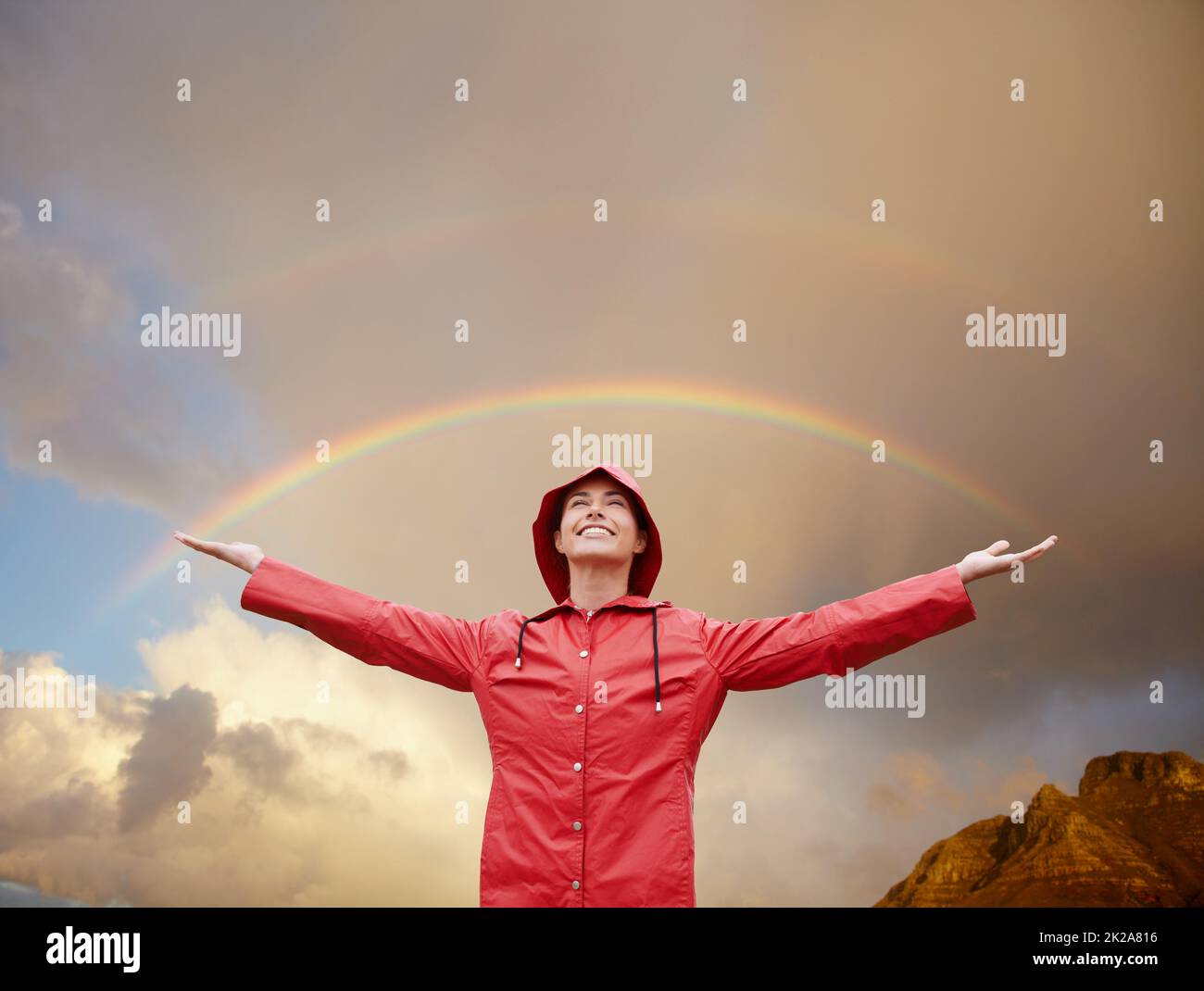 Shes fand ihren Regenbogenmoment. Kurzer Schuss einer attraktiven jungen Frau, die im Regen steht. Stockfoto