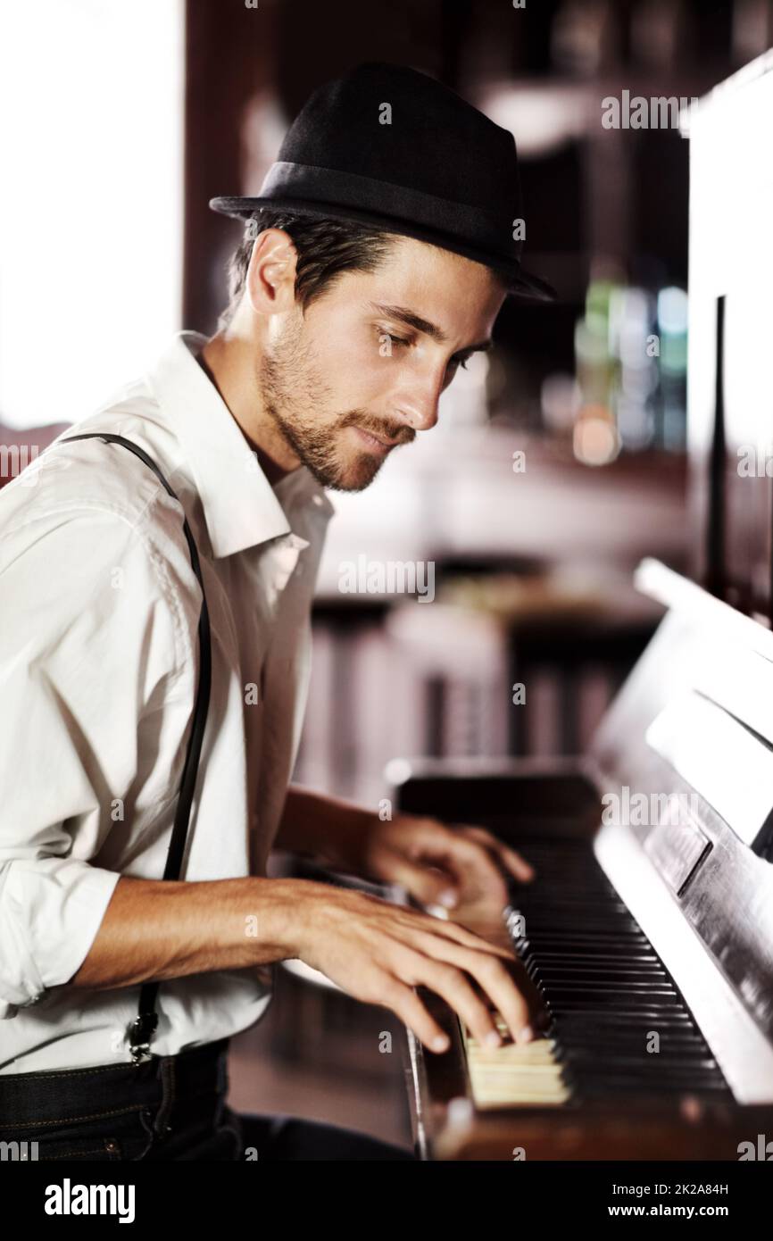 Die Musik aus dem tiefsten Inneren seiner Seele auszudrücken. Ein hübscher junger Mann, der in einem Club Klavier spielt. Stockfoto