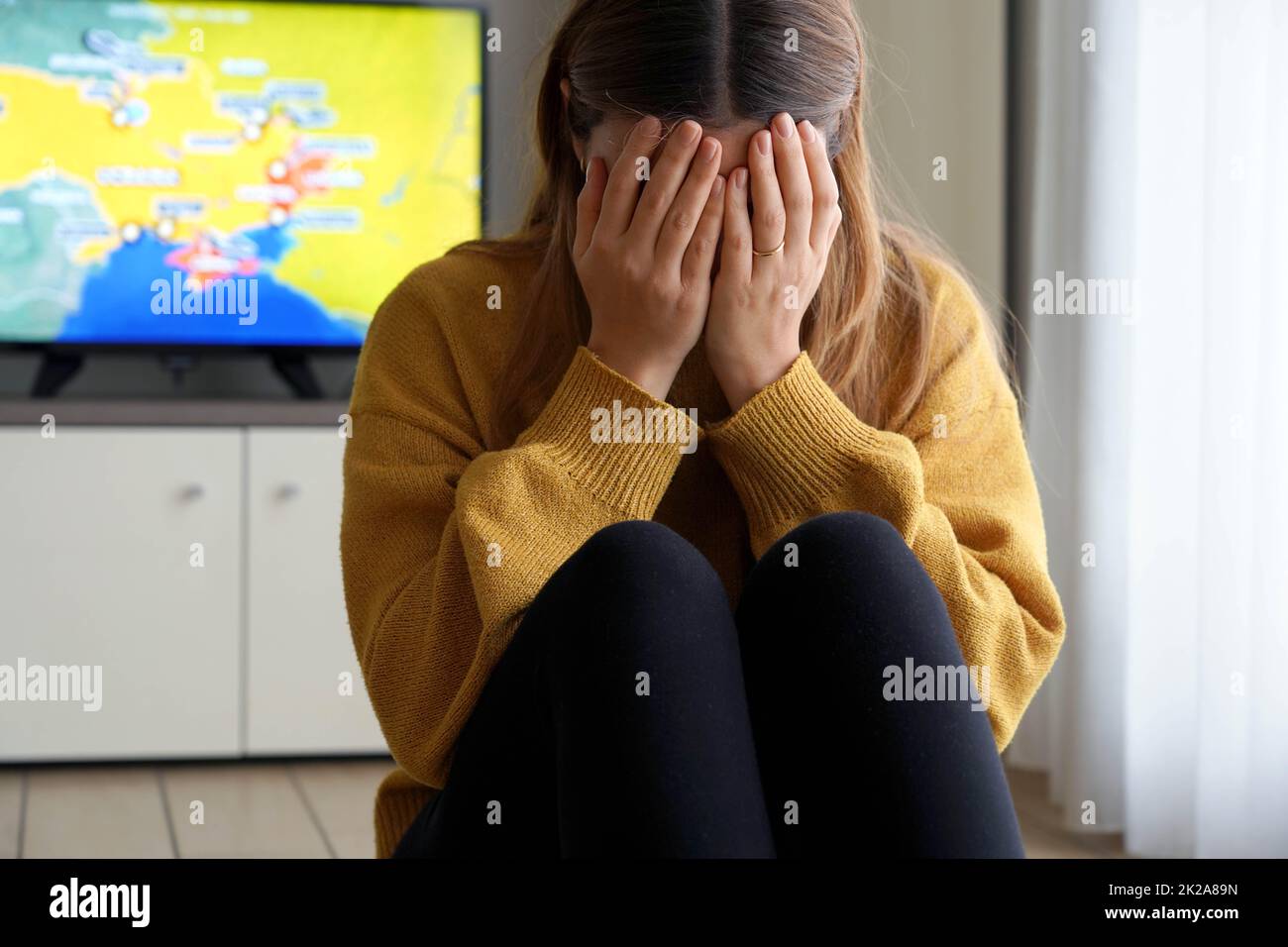 Russische Invasion der Ukraine. Mädchen weint zu Hause während Bomben Angriff draußen auf der Straße. Stockfoto