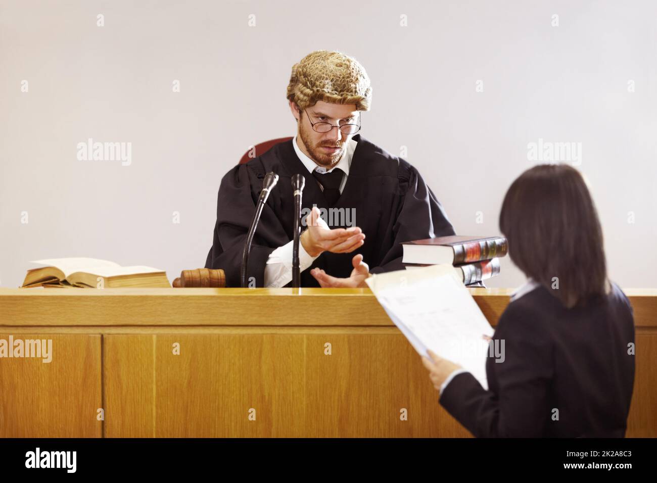Präsentieren Sie Ihren Fall.... Seriöse junge Richterin sitzt im Gerichtssaal mit strengem Gesichtsausdruck. Stockfoto