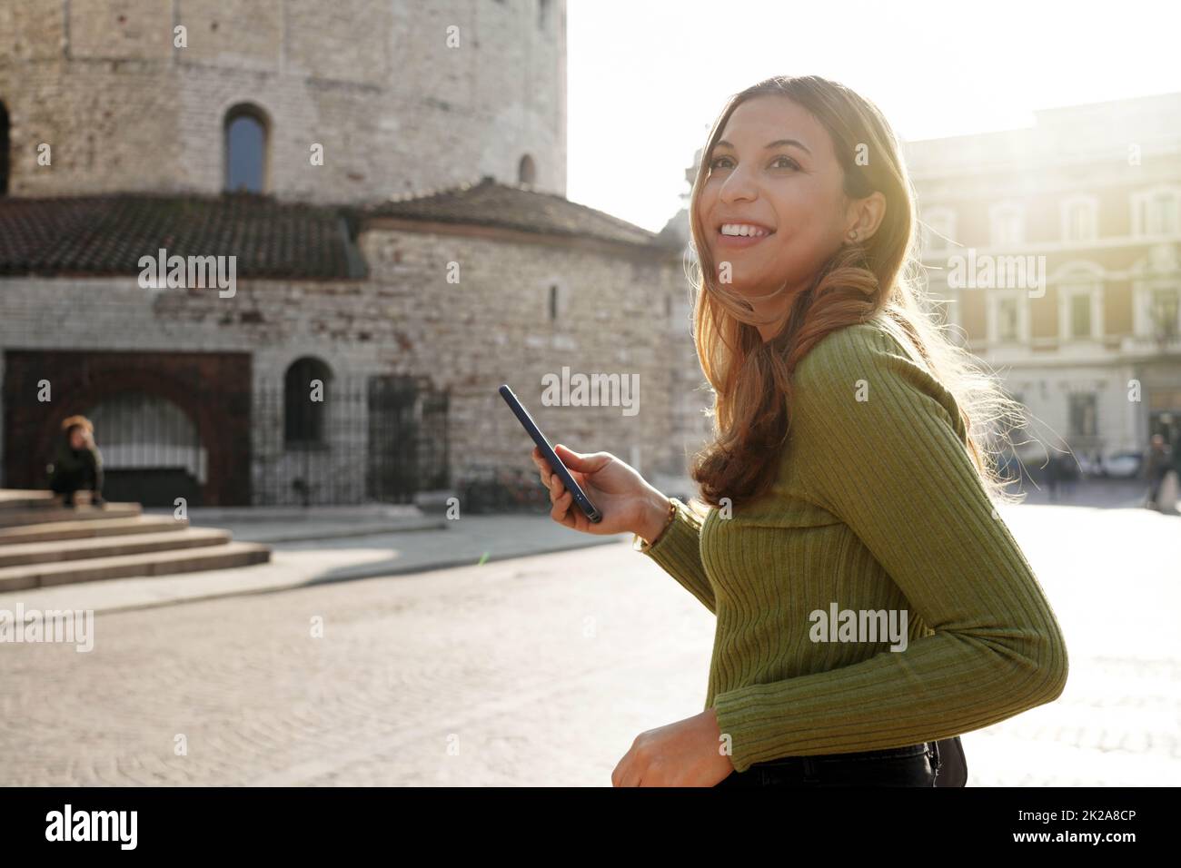 Schönes lächelndes Mädchen, das in Brescia, Italien, mit dem Telefon unterwegs ist Stockfoto