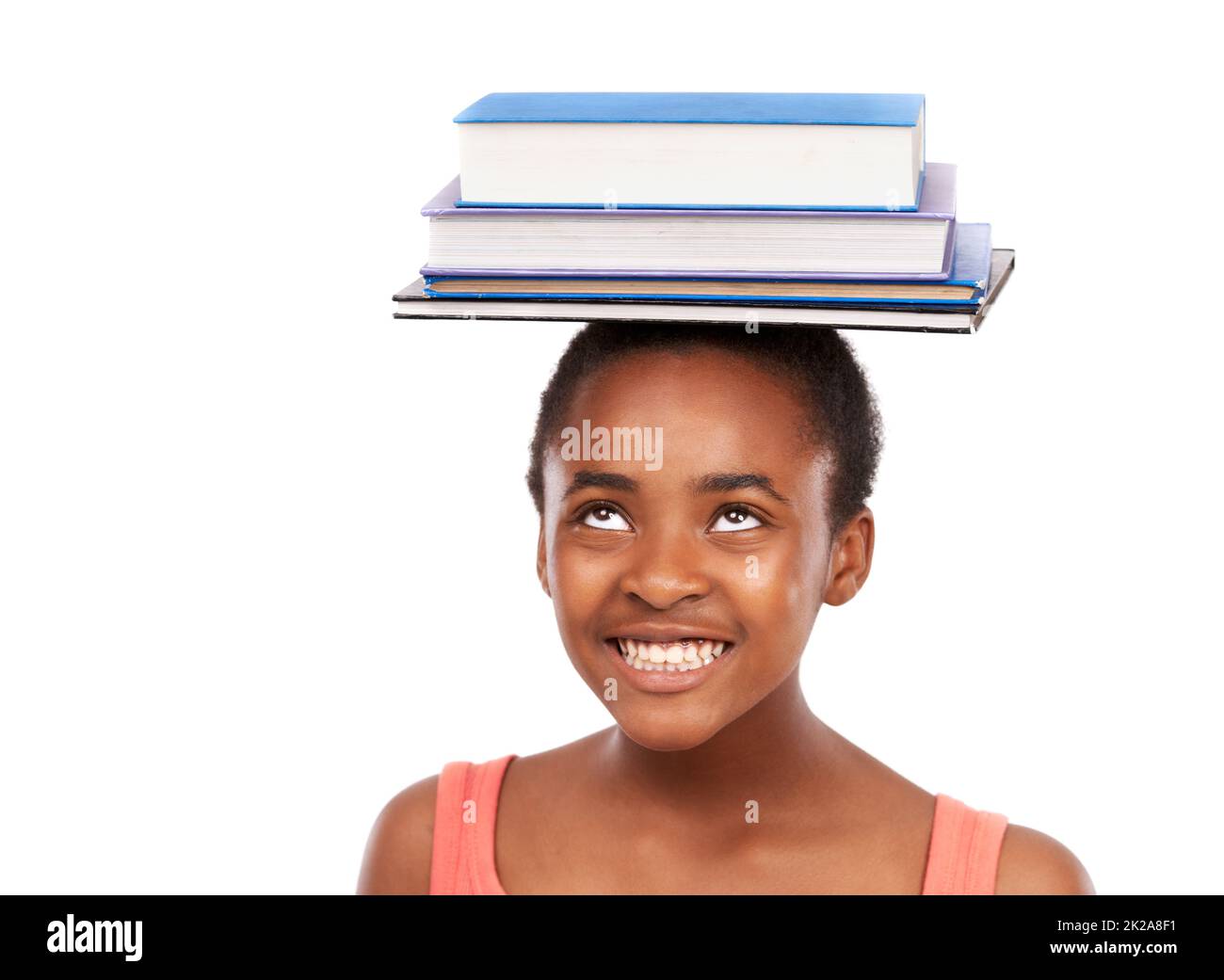 Ich perfektioniere mein Gleichgewicht. Studioaufnahme eines jungen afrikanischen Mädchens, das auf weißem Kopf Bücher balanciert. Stockfoto
