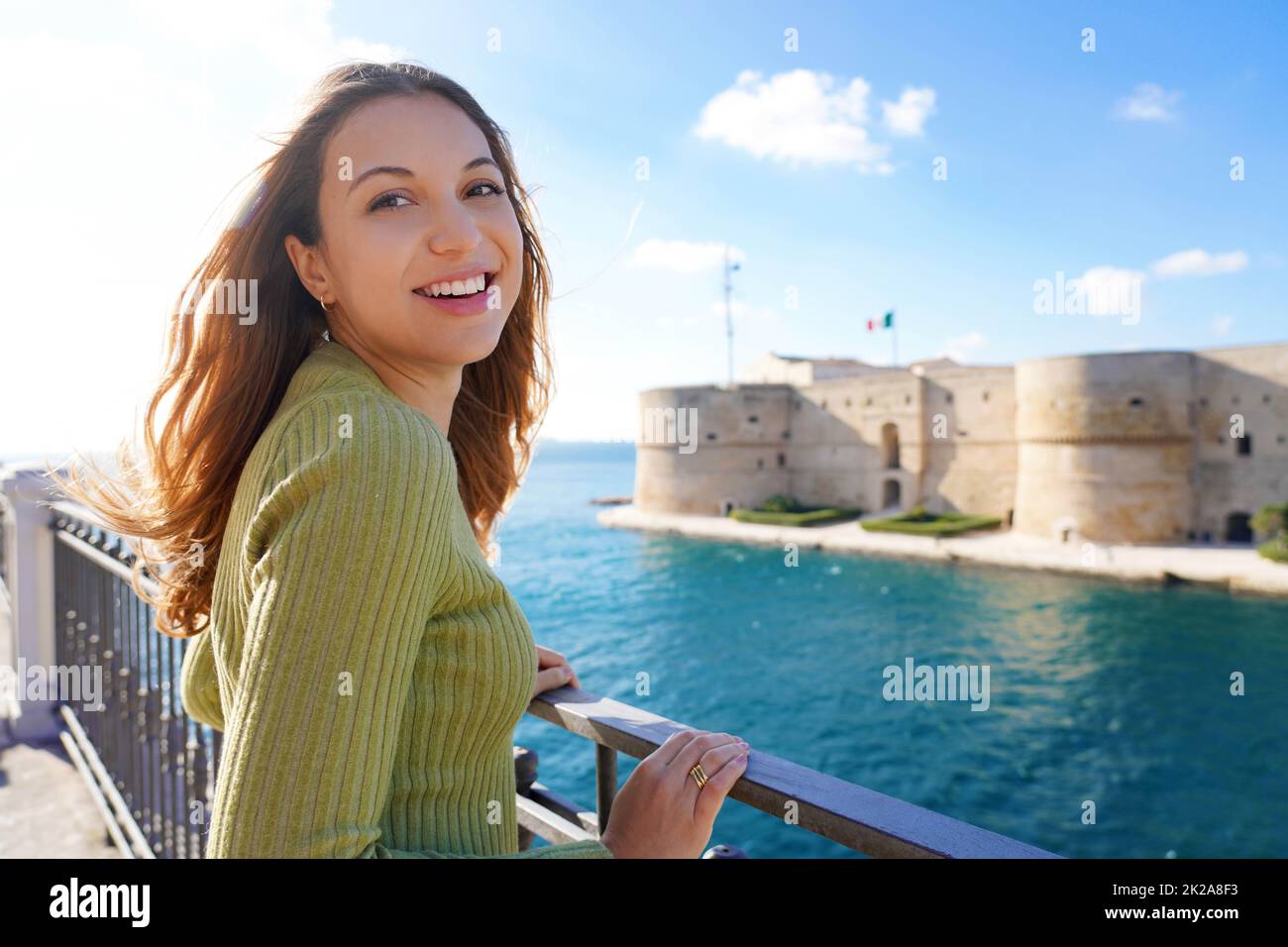 Porträt einer lächelnden, entspannten Frau, die mit Taranto-Strand im Hintergrund die Kamera anschaut, Apulien, Italien Stockfoto
