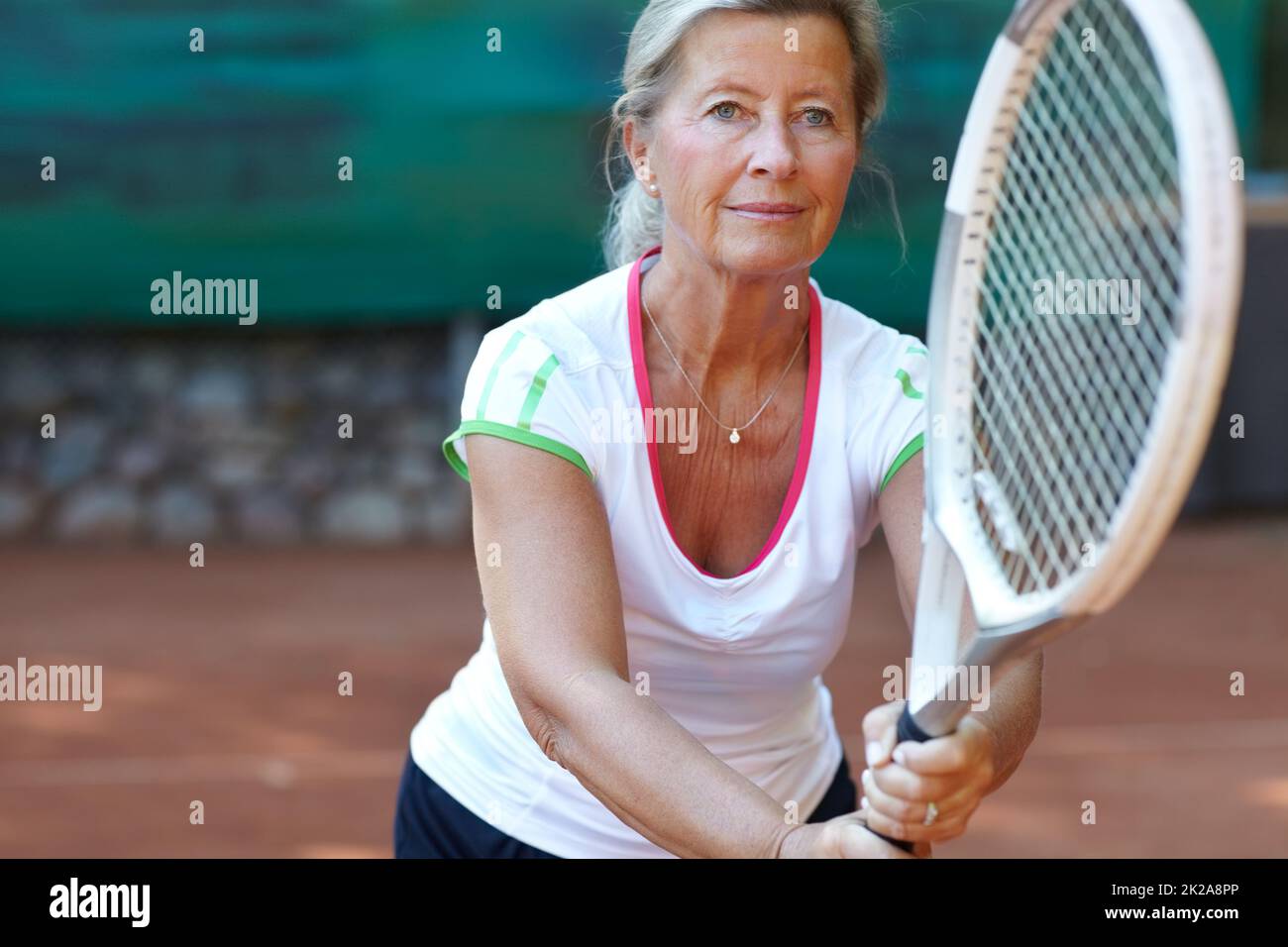 Engagierter Tennisspieler. Ältere Frau, die sich darauf vorbereitet, während eines Tennisspiels einen Aufschlag zurückzugeben. Stockfoto