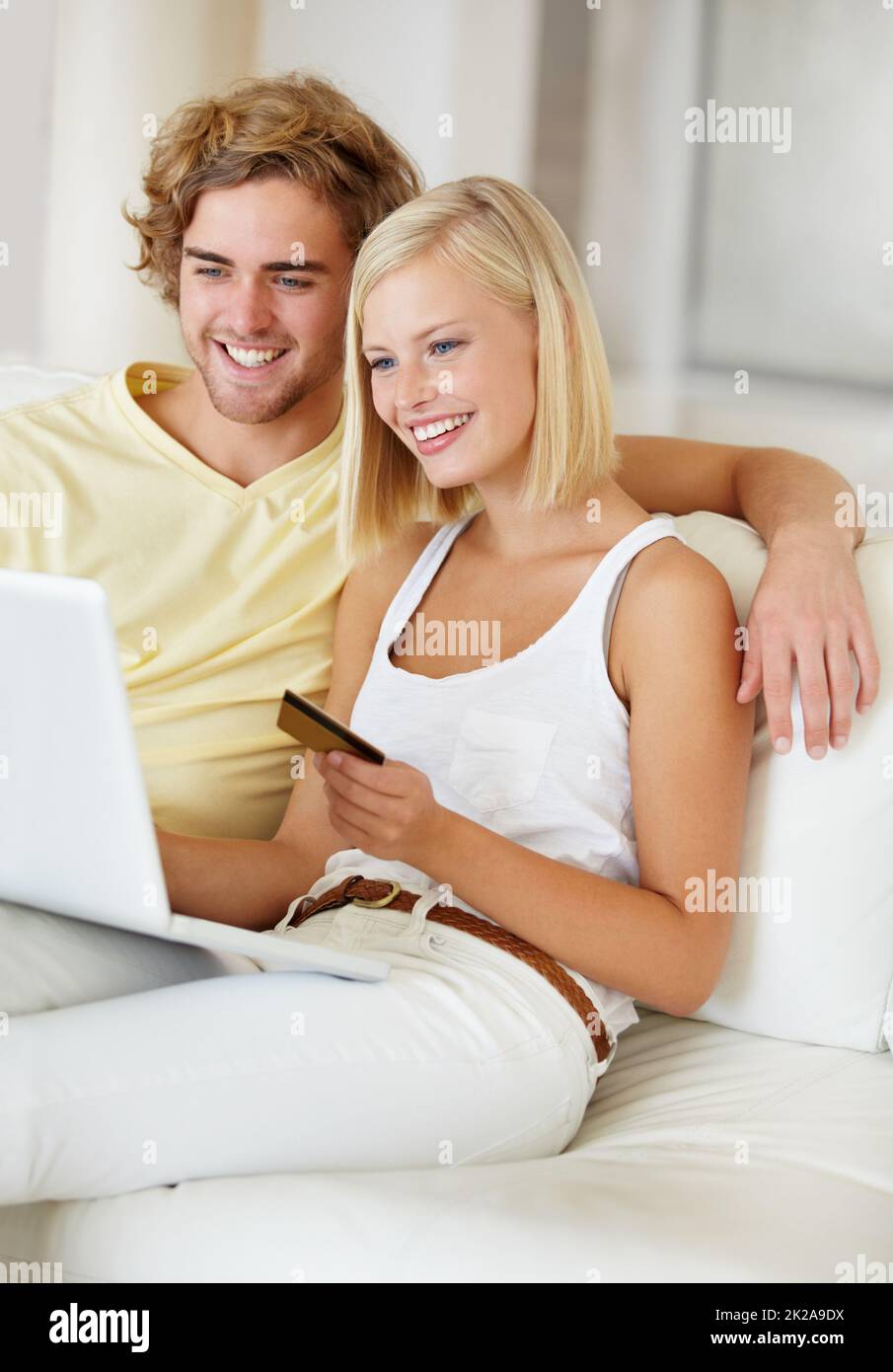 Auf der Suche nach etwas für ihr neues Haus. Ein glückliches junges Paar, das sein Online-Banking bequem von der Couch aus macht. Stockfoto