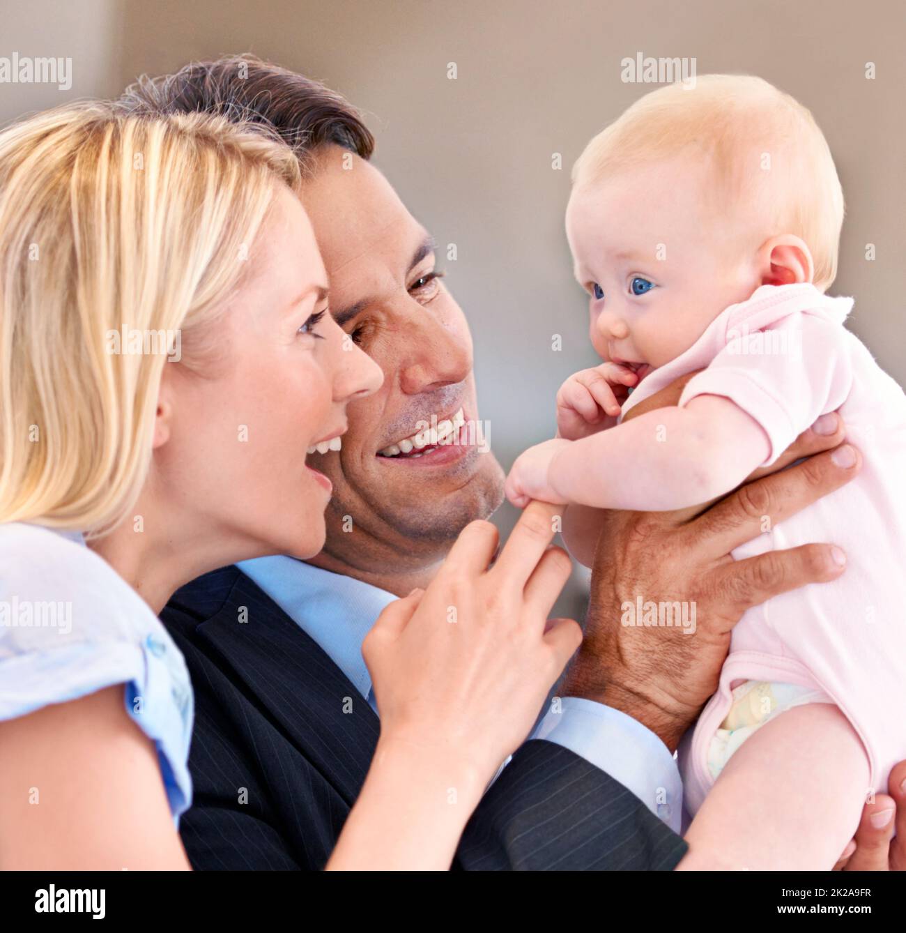 Schaut auf ihre schönen blauen Augen. Junge Mutter und Vater kichern mit ihrem Baby. Stockfoto