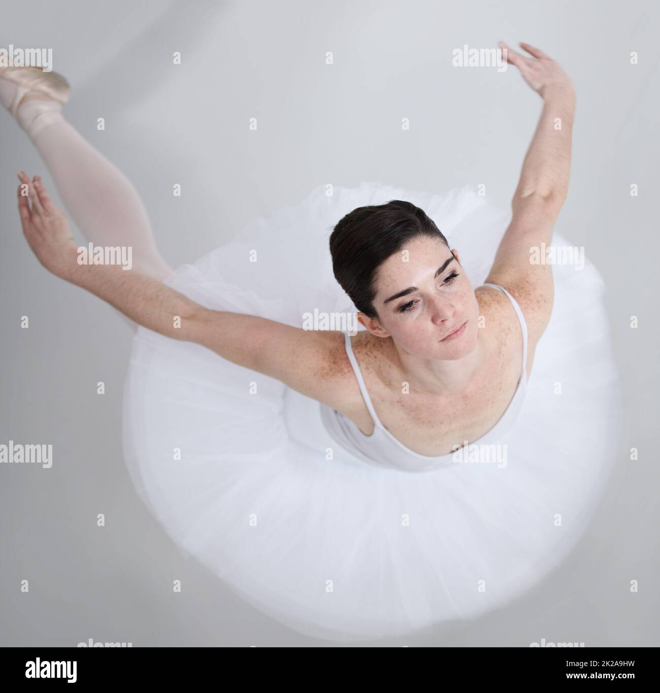 Voller Eleganz und Anmut. Geschmeidige junge Ballerina, die vor weißem Hintergrund tanzt. Stockfoto