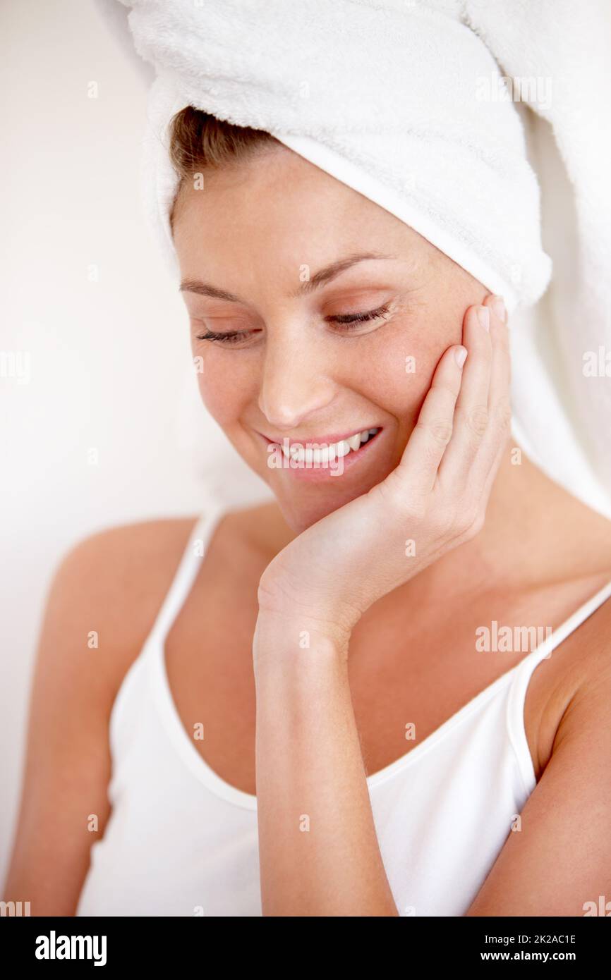 Erstaunt, wie glatt ihre Haut ist. Eine schöne junge Frau, die ihre glatte Haut nach einer erfrischenden Dusche spürt. Stockfoto