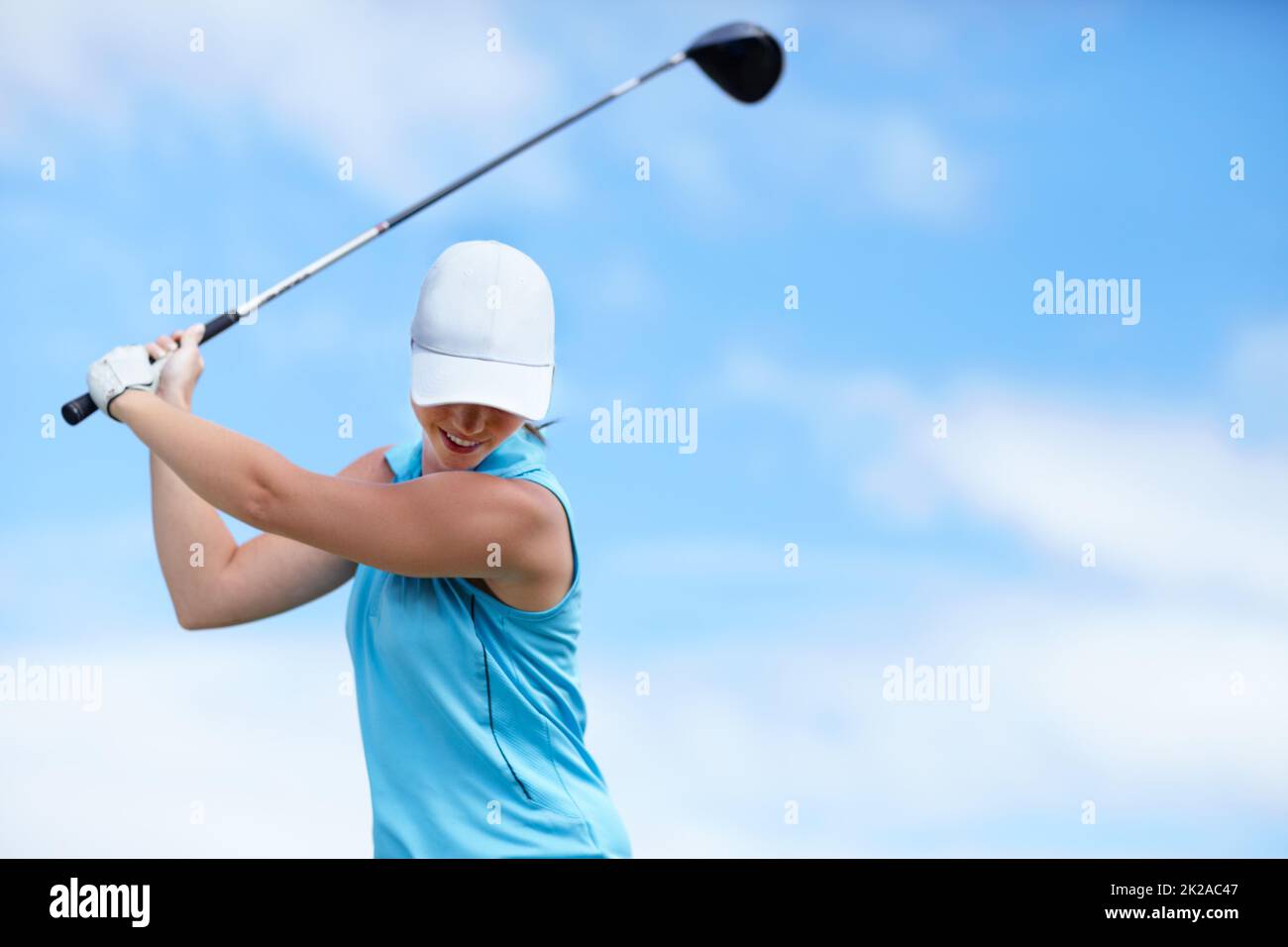 Der Trick ist, den Kopf zu halten. Eine junge Golfspielerin schwingt einen Golfclub (Fahrer) über ihren Kopf, um einen Schuss zu machen - Copyspace. Stockfoto