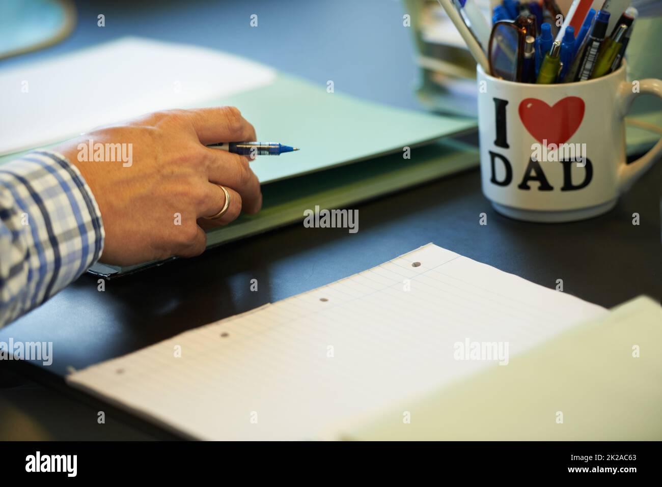 Er ist stolz auf seinen Arbeitsplatz. Zugeschnittenes Bild eines Geschäftsmanns, der mit Papierkram und Schreibwaren vor ihm an seinem Schreibtisch sitzt. Stockfoto