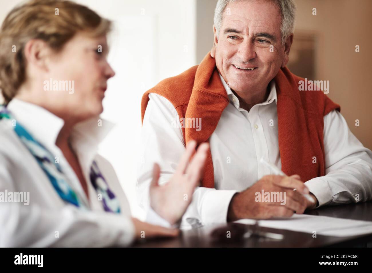 Unterhaltung an der Rezeption. Ein älterer Mann und seine Frau füllen an der Rezeption des Hotels Formulare aus. Stockfoto