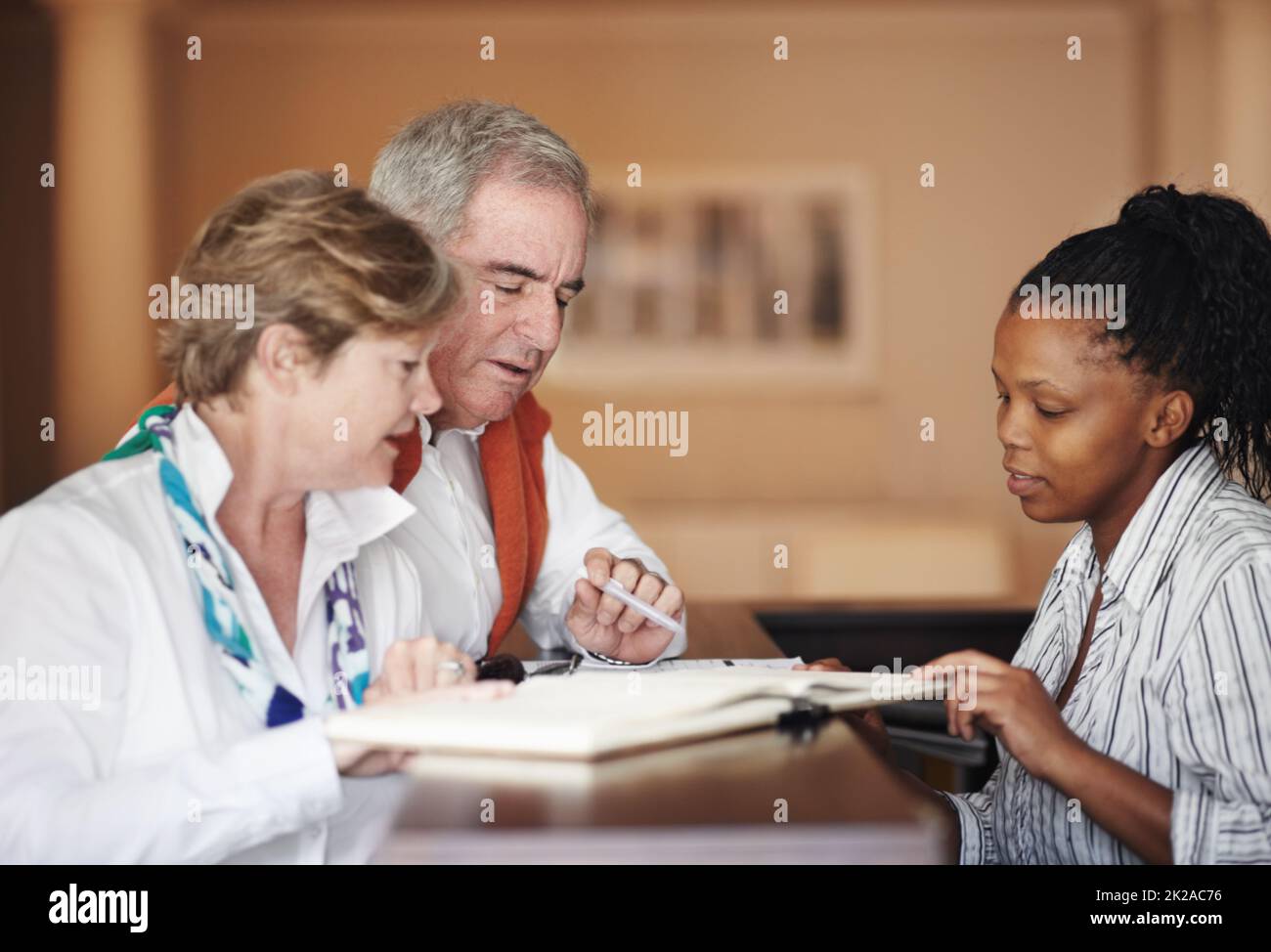 Freundliche Unterstützung an der Rezeption. Ein Seniorenpaar füllt Formulare an der Rezeption aus. Stockfoto