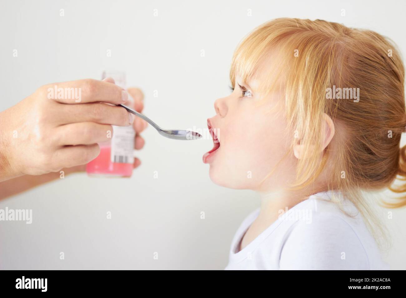 Shes ein wachsendes Mädchen. Ein niedliches Mädchen mit offenem Mund, das mit einem Löffel gefüttert werden kann. Stockfoto