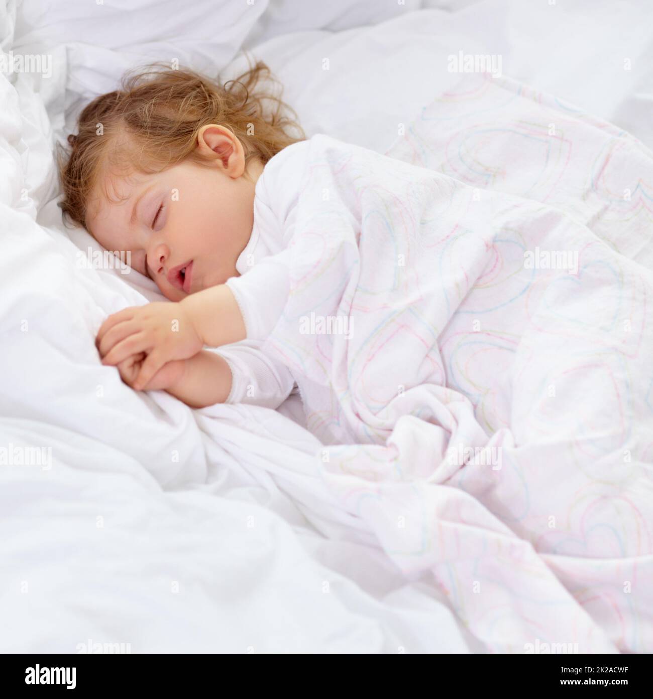 Schlaf ist wichtig für die Entwicklung. Ein süßes Baby, das auf dem Bett schläft. Stockfoto