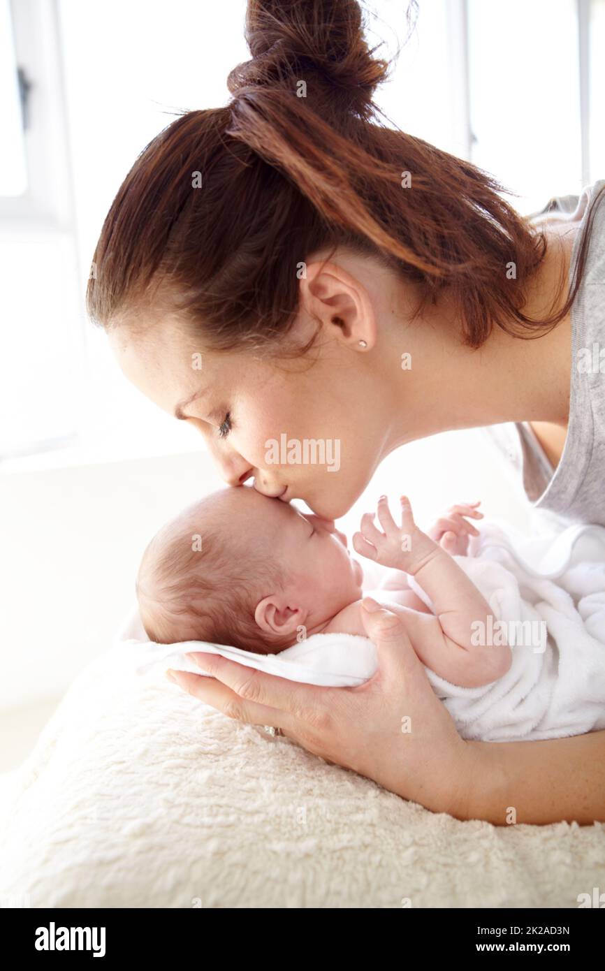 Es gibt keine Liebe wie die einer Mutter. Nahaufnahme einer Mutter, die ihr neugeborenes Baby zärtlich küsst. Stockfoto