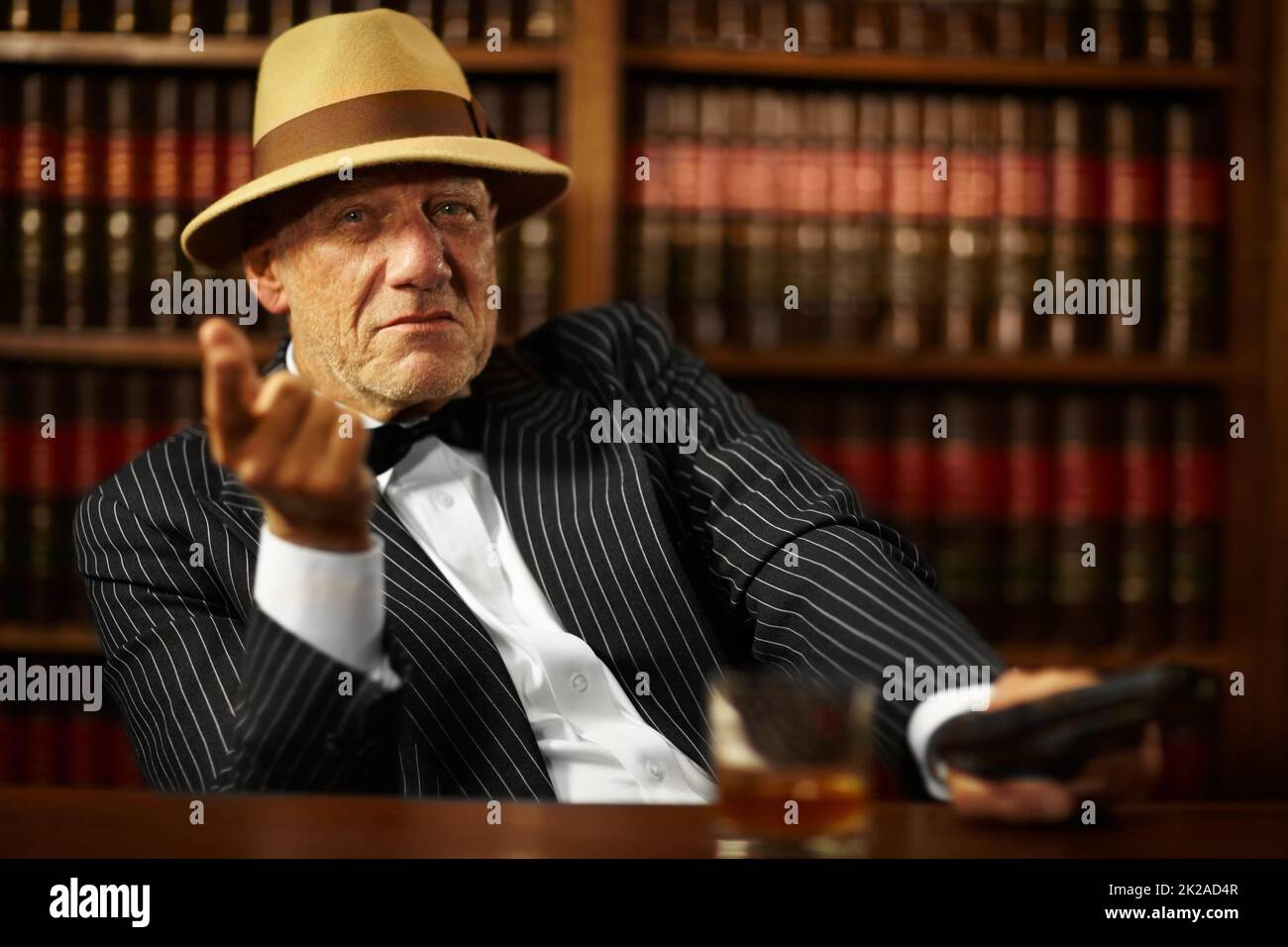 Er leitet eine große kriminelle Organisation. Gealterter Mob-Boss, der einen Hut trägt und beim Zeigen ernst aussieht. Stockfoto