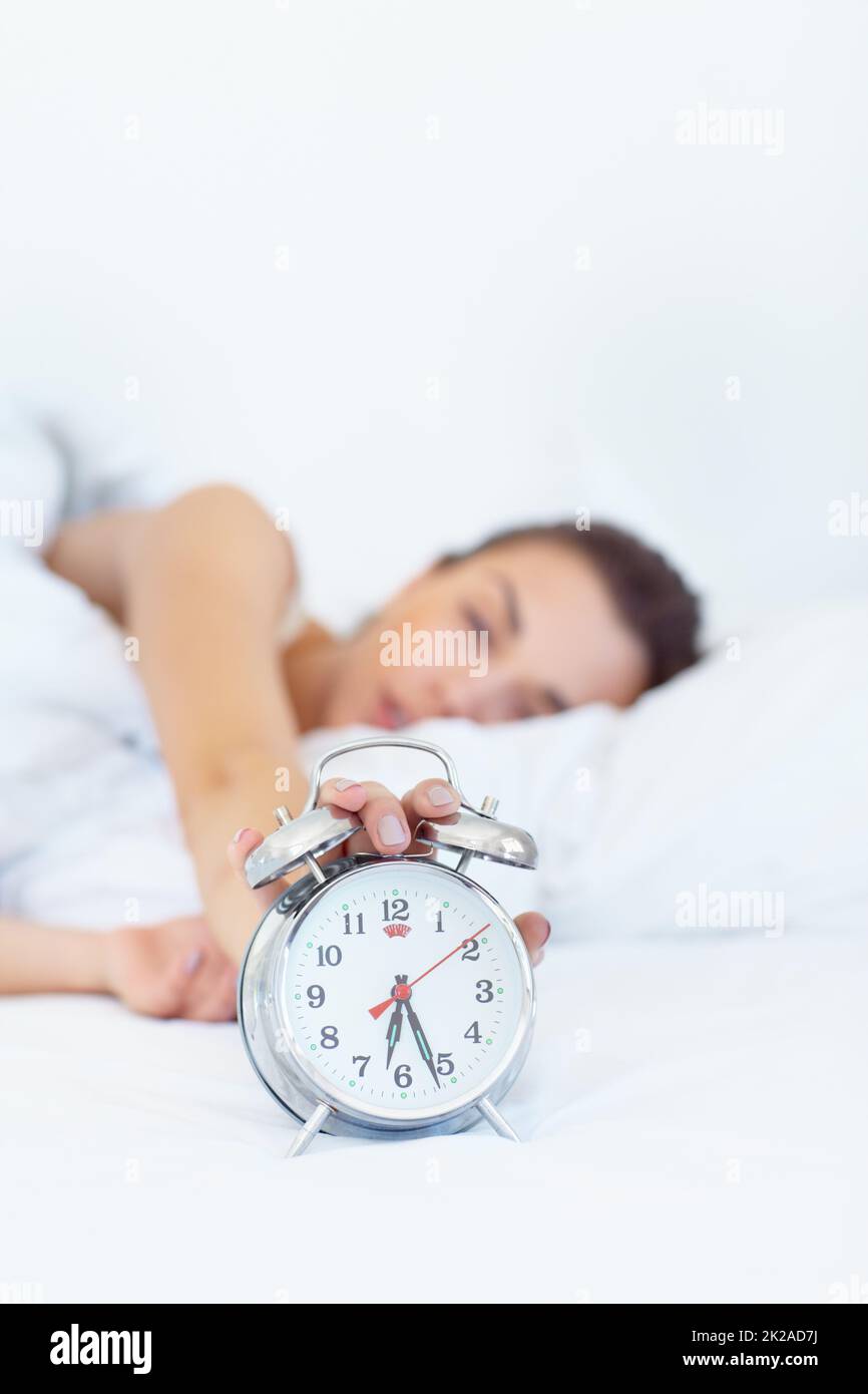 5 weitere Minuten.... Aufnahme einer verdummten jungen Frau, die sich nach draußen griff, um ihren Wecker auszuschalten. Stockfoto