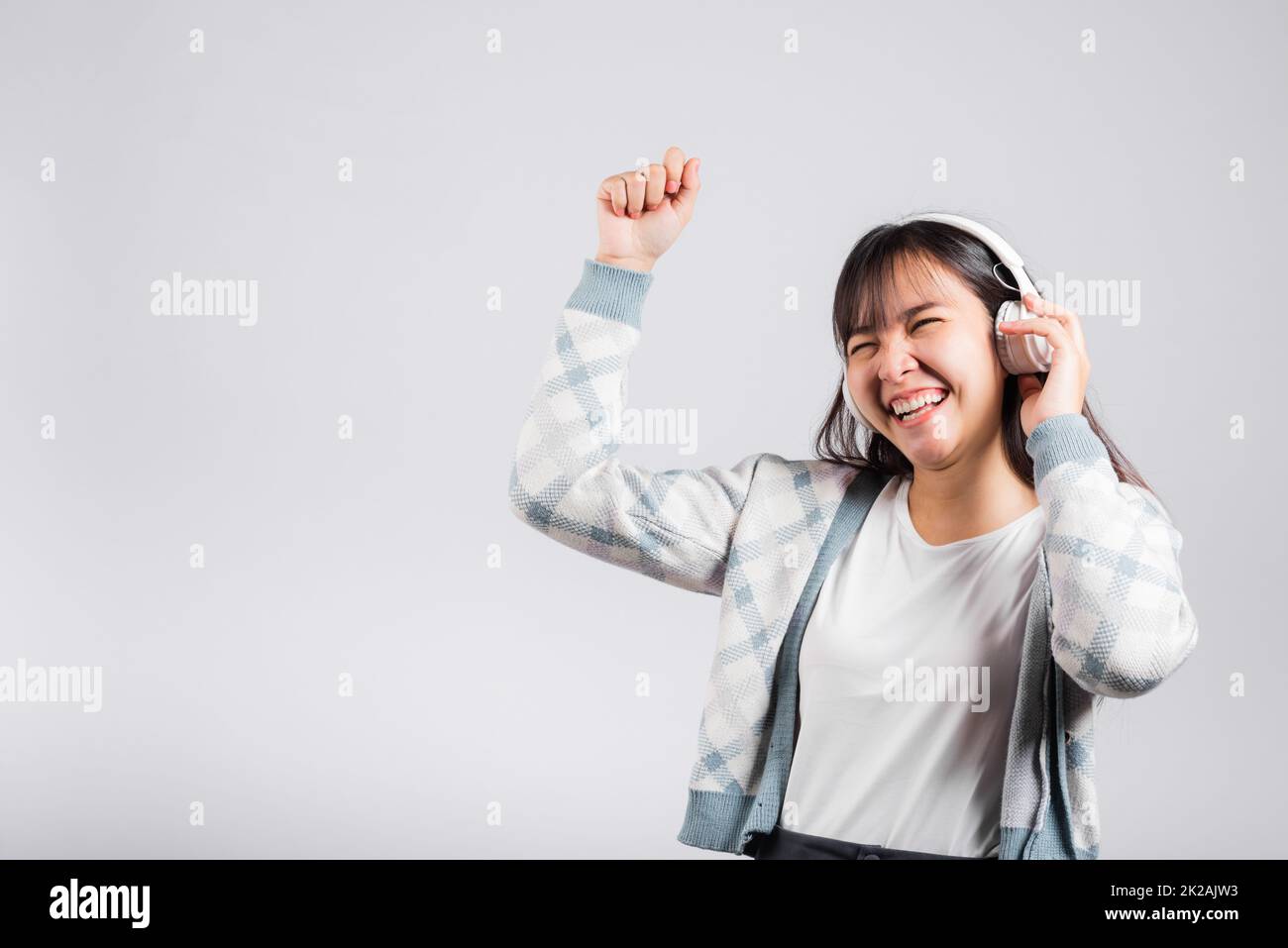 Eine Frau, die mit ihrem Lächeln Musik über bluetooth ® Kopfhörer hört und mit ihrem Smartphone tanzt Stockfoto