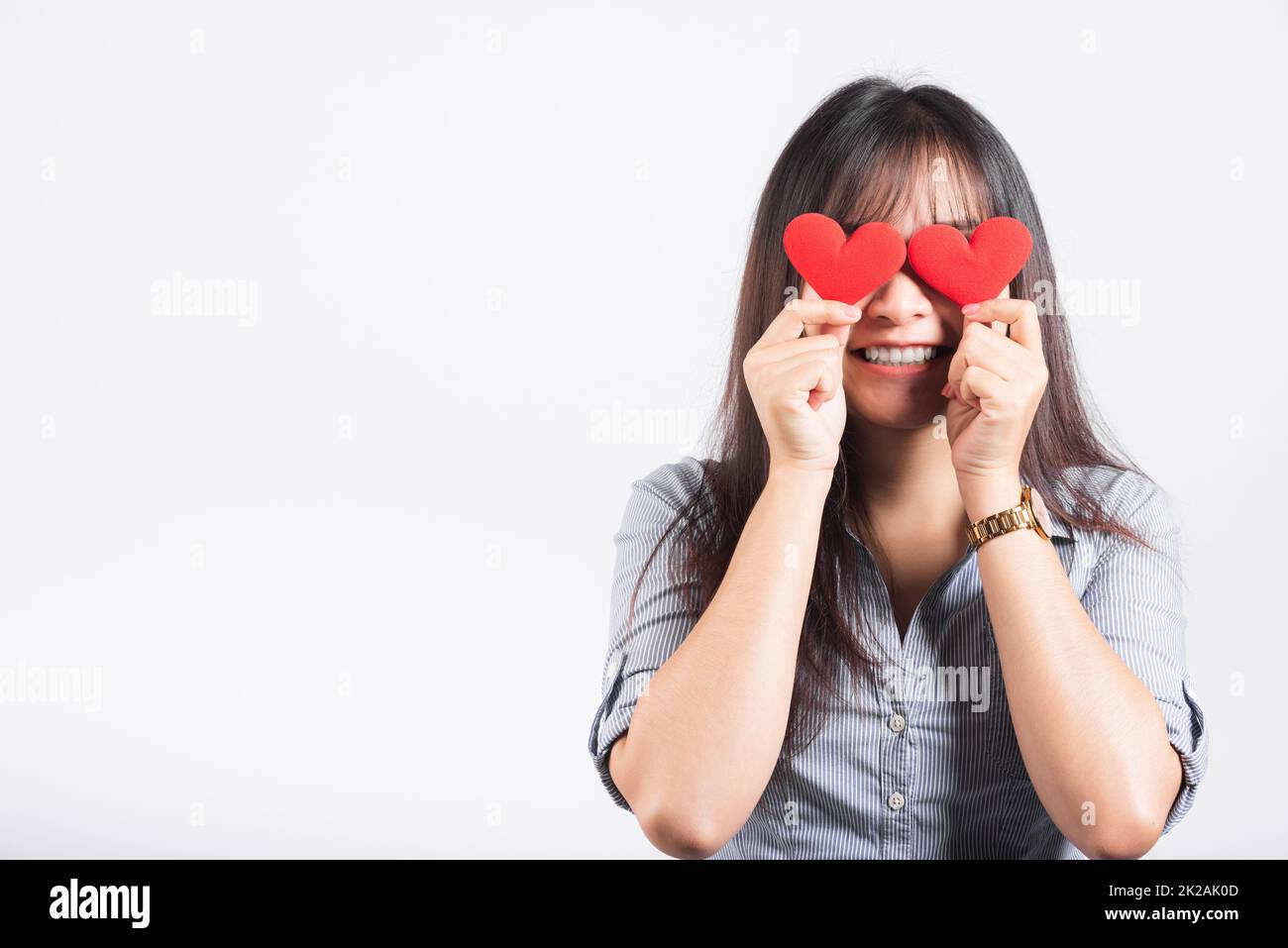 Frau steht ihr Lächeln selbstbewusst fröhliches Mädchen hält zwei rote Herzkarten in den Händen und schließt die Augen Stockfoto