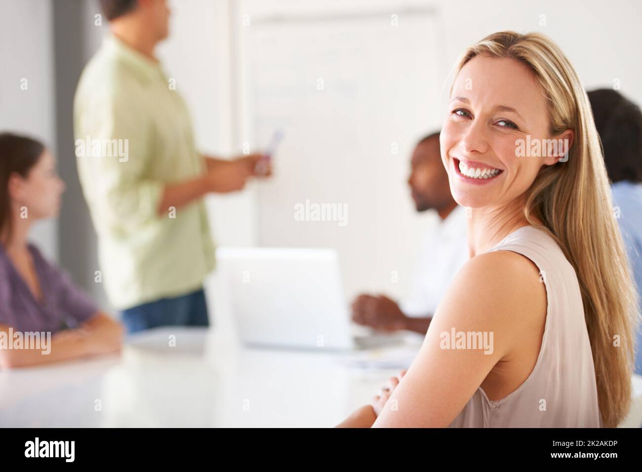 Inhalte in ihrer Karriere und ihrem Team. Eine lächelnde Geschäftsfrau, die Sie während eines Teammeeting ansieht. Stockfoto