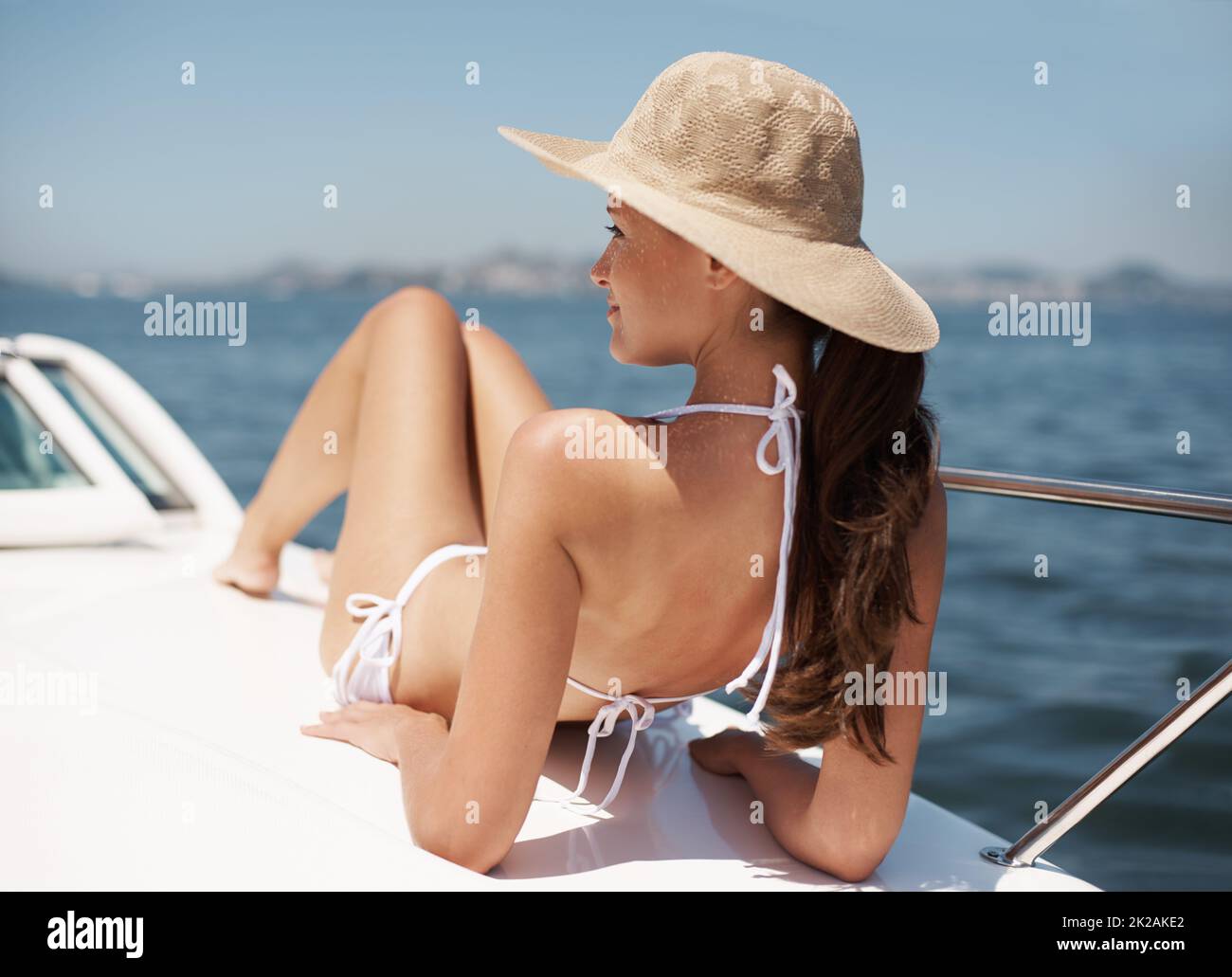 Die Strahlen fangen. Eine attraktive junge Frau, die auf dem Deck einer Luxusyacht bräunt. Stockfoto