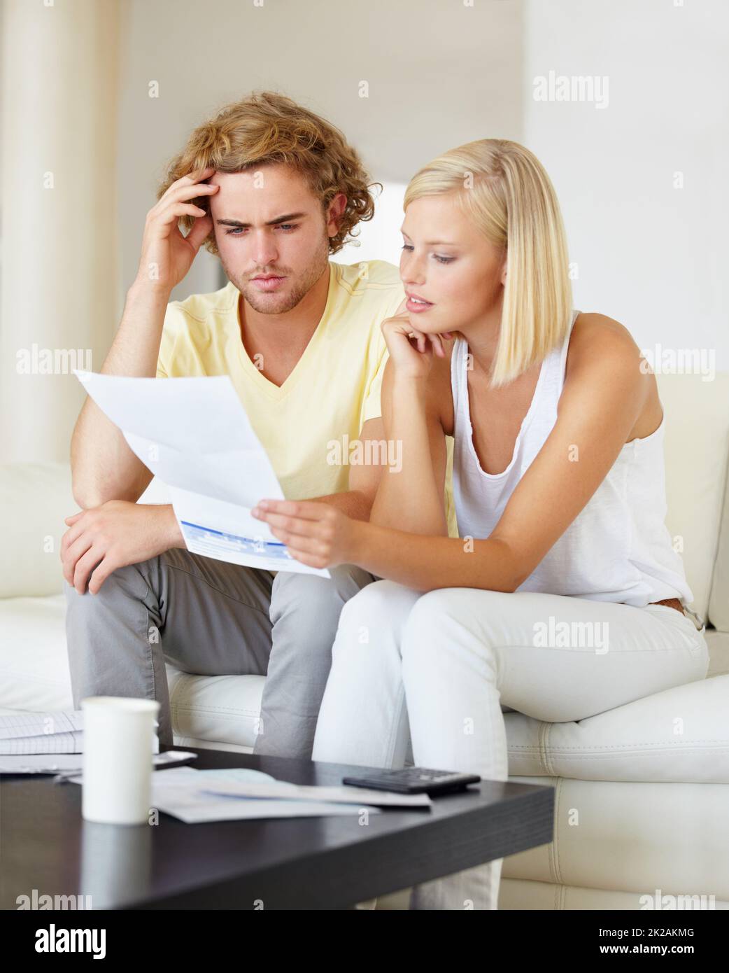 Woher kommen all diese Rechnungen? Ein junges Paar, das zusammen in der Lounge einen Finanzbericht liest. Stockfoto