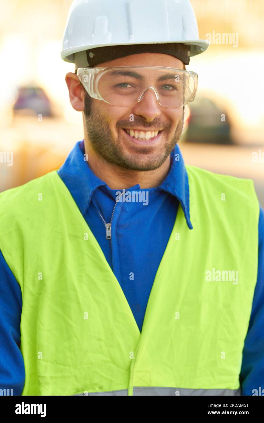 Erfolgreicher Ingenieur. Porträt eines Bauarbeiters, der eine Schutzbrille trägt und Sie lächelt. Stockfoto