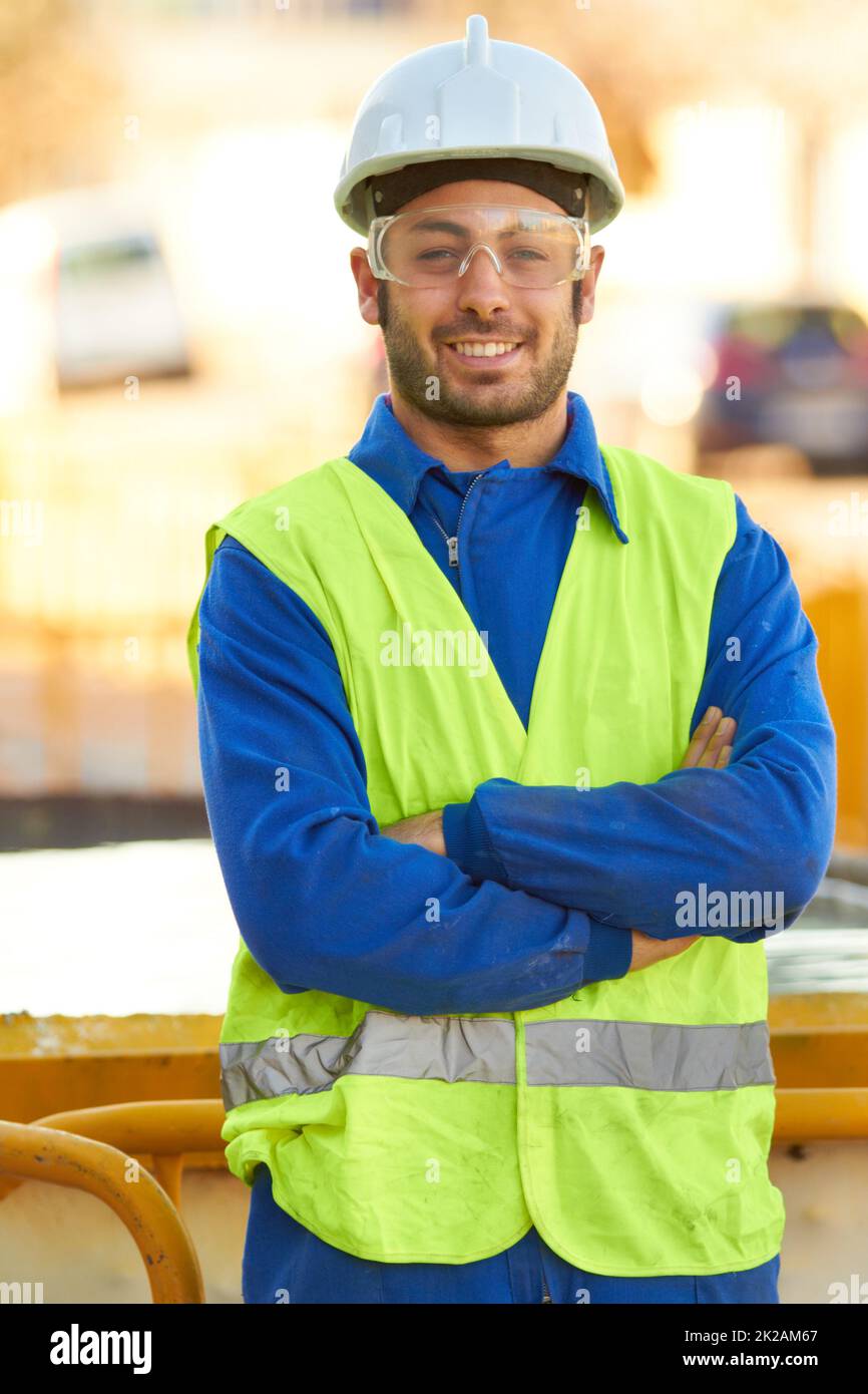 Vertrauen in seine Konstruktionsfähigkeit. Porträt eines Bauarbeiters, der eine Schutzbrille trägt und Sie lächelt. Stockfoto