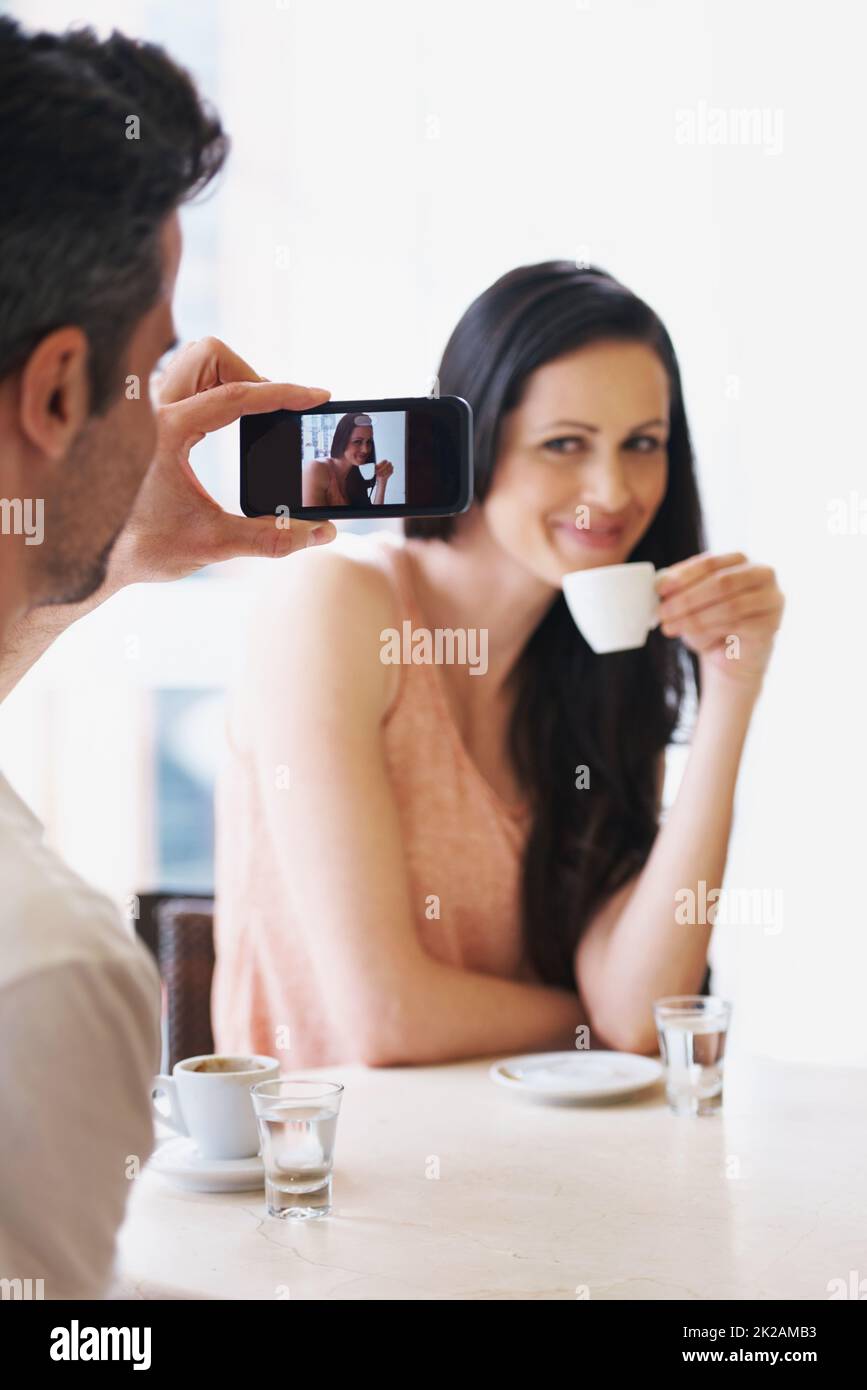 Halte die Pose. Aufnahme eines Mannes, der in einem Café mit seinem Telefon eine Momentaufnahme seiner Frau machte. Stockfoto