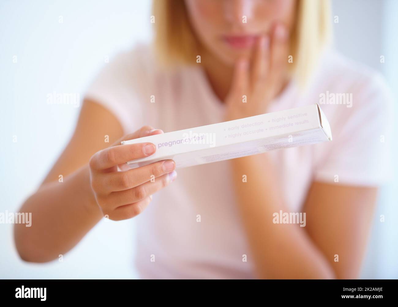 Sie muss den Test machen. Eine junge Frau, die nervös vor einem Schwangerschaftstest steht. Stockfoto