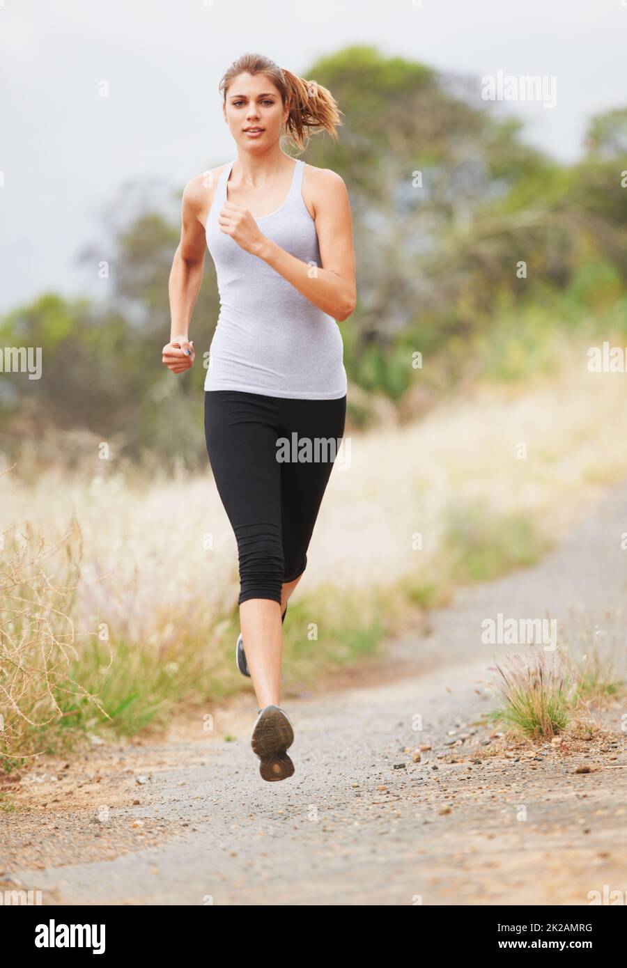Laufen für Fitness. Eine junge Frau, die auf einer unbefestigten Straße läuft. Stockfoto