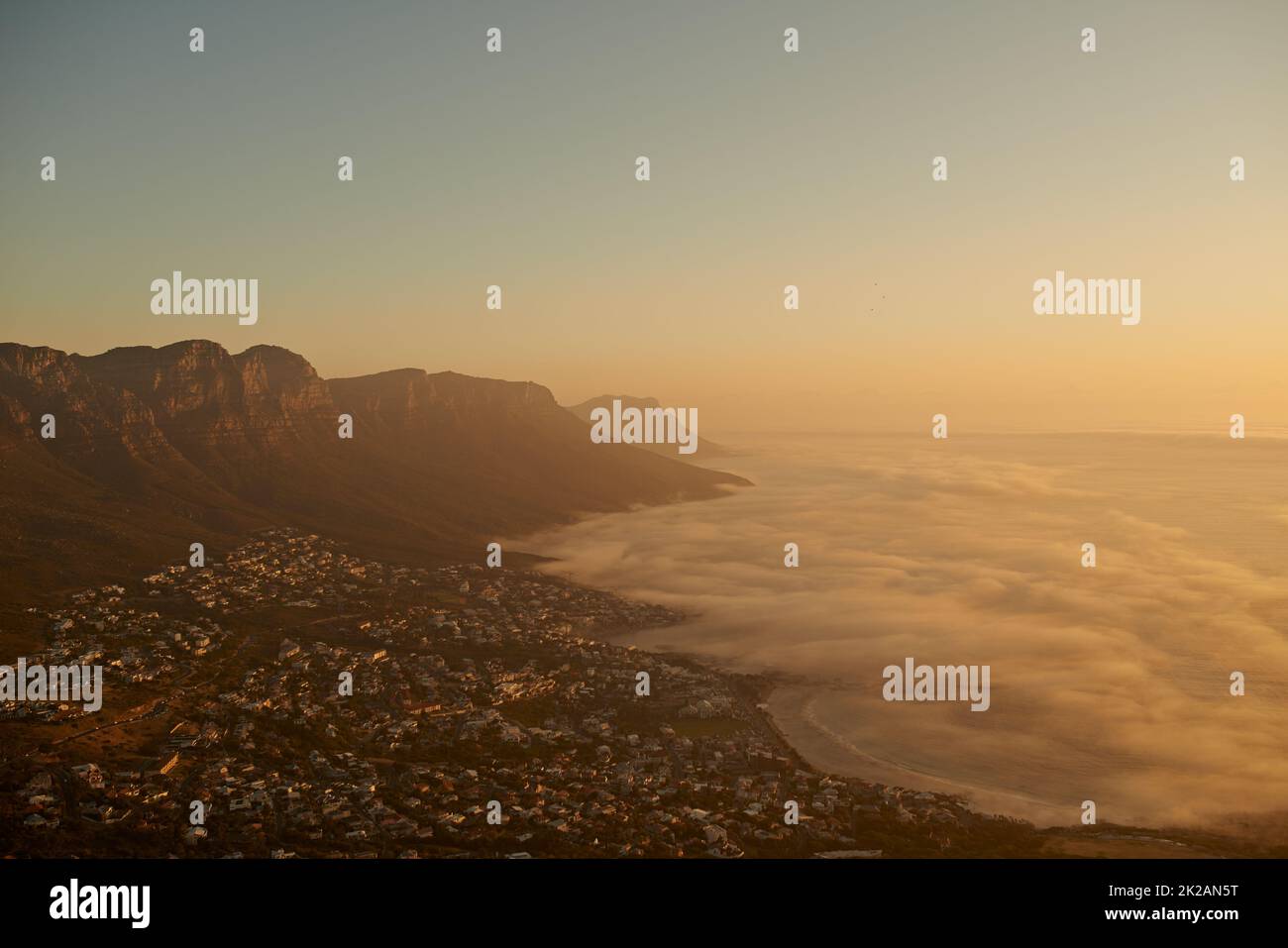 Über den Berg, über das Meer. Aufnahme einer Küstenstadt an einem Berghang am Abend. Stockfoto