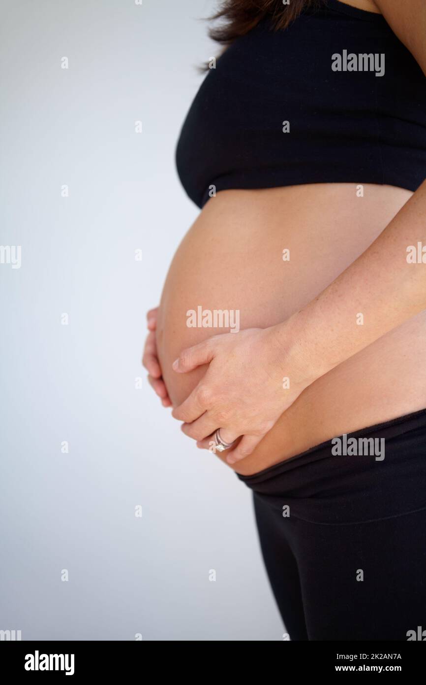 Ich kann es kaum erwarten, mein Kind zu halten. Werdende Mutter hält ihren schwanger Bauch - abgeschnitten. Stockfoto