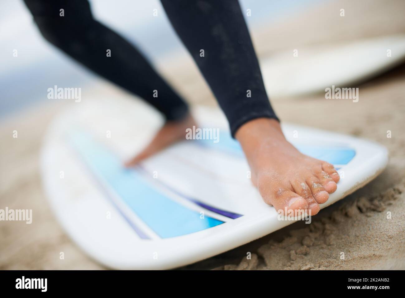 Ein Gefühl für das Board zu bekommen. Zugeschnittene Aufnahme einer nicht erkennbaren Surferin mit Füßen auf einem Surfbrett. Stockfoto