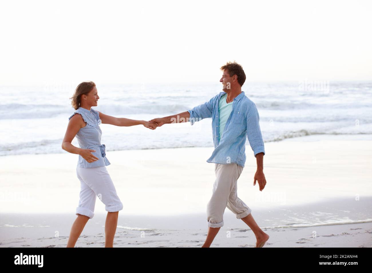 Tango am Strand. Ein glückliches Paar, das sich die Hände während der Sonnenuntergänge am Strand hielt. Stockfoto