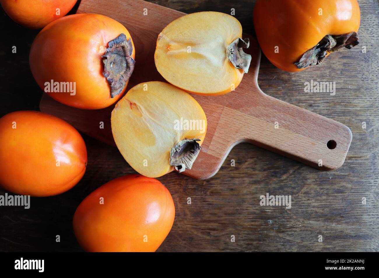 Frische Bio reife Kaki Früchte mit Scheibe auf alten Holztisch Hintergrund. Draufsicht. Flach liegend. Platz für Text und Inhalt kopieren Stockfoto