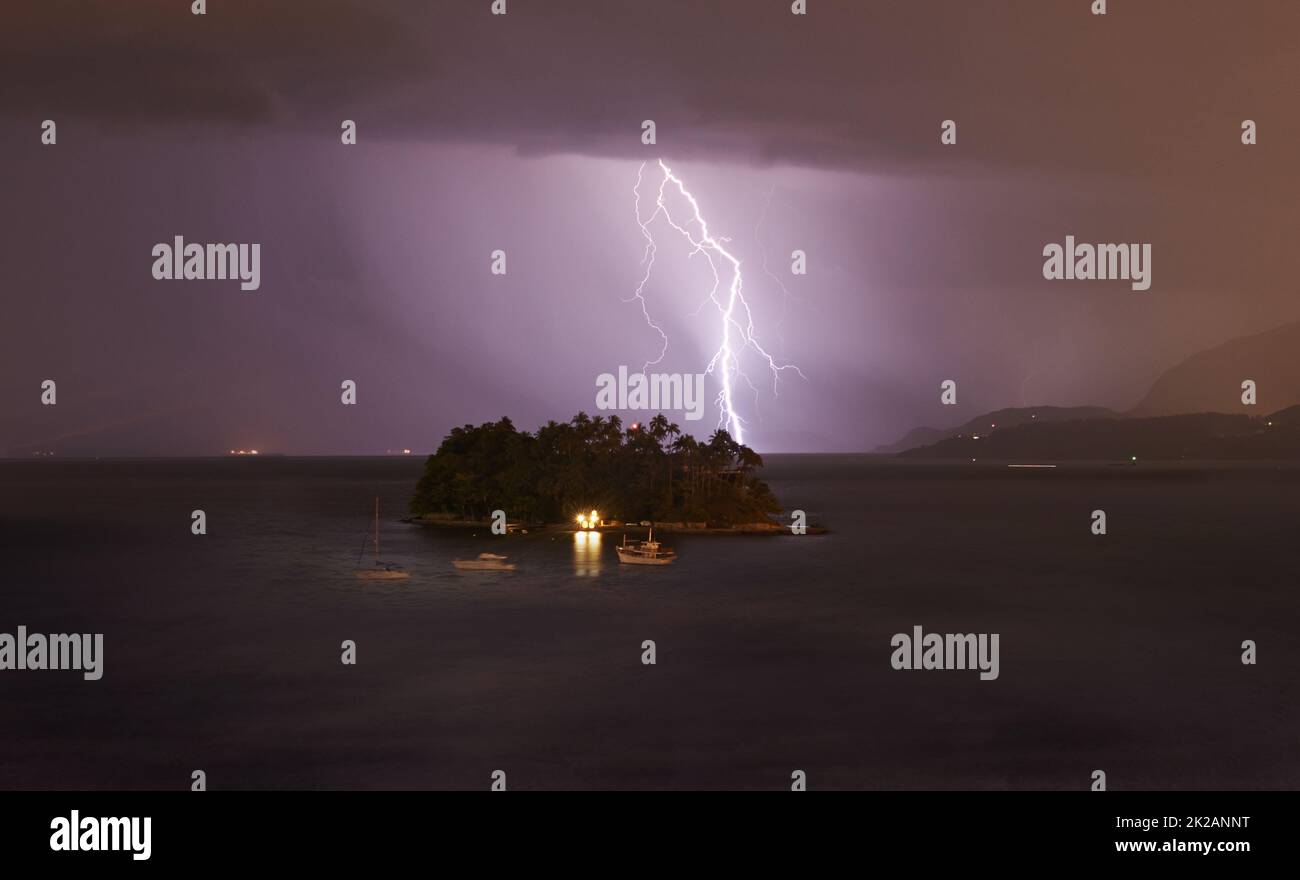 Das Wetter war launisch. Blitzschlag auf eine kleine Insel bei einem nächtlichen Sturm. Stockfoto