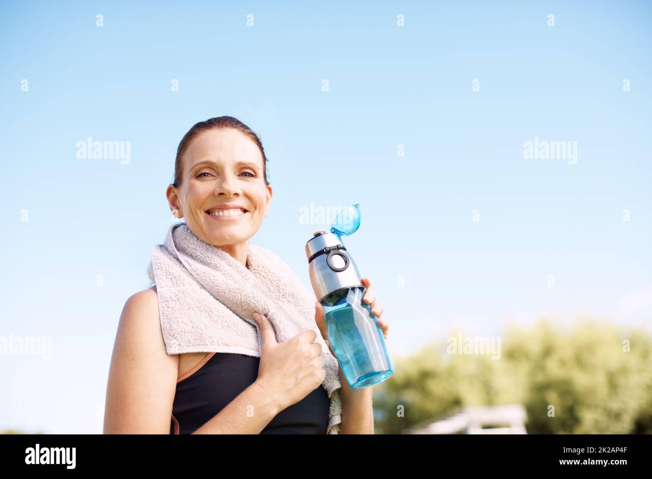 Ich fühle mich gestärkt. Eine attraktive Frau, die nach einem Workout im Freien mit ihrer Wasserflasche steht. Stockfoto