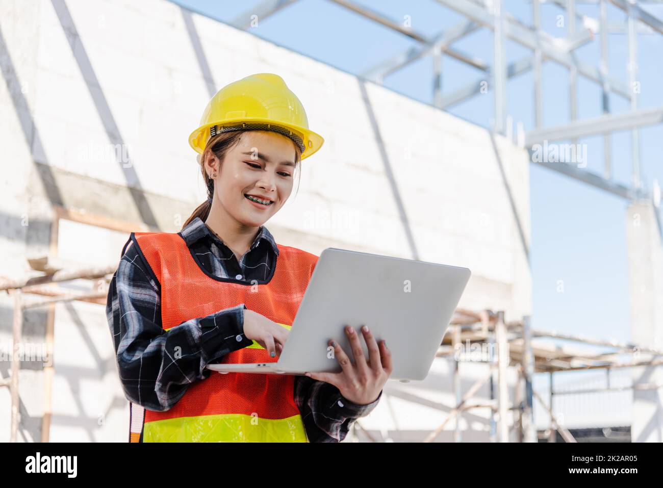 Asiatische Architektenfrau mit Laptop inspiziert und überwacht den Fortschritt der Infrastruktur auf der Baustelle Stockfoto