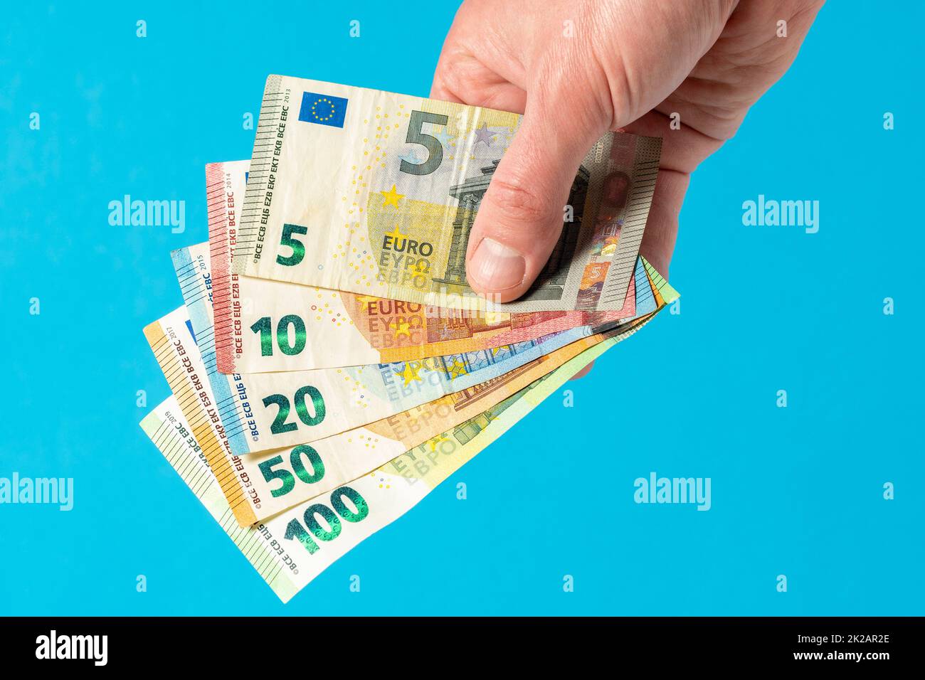 Hand mit Euro-Banknoten auf blauem Hintergrund Stockfoto