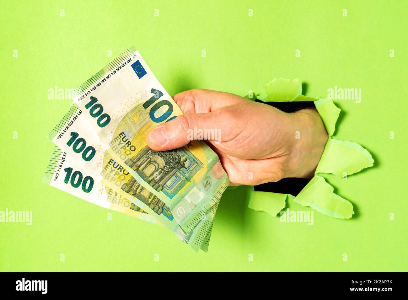 Ein Geschäftsmann, der mit einem Haufen Euro-Scheine ein Grünbuch durchbrach Stockfoto