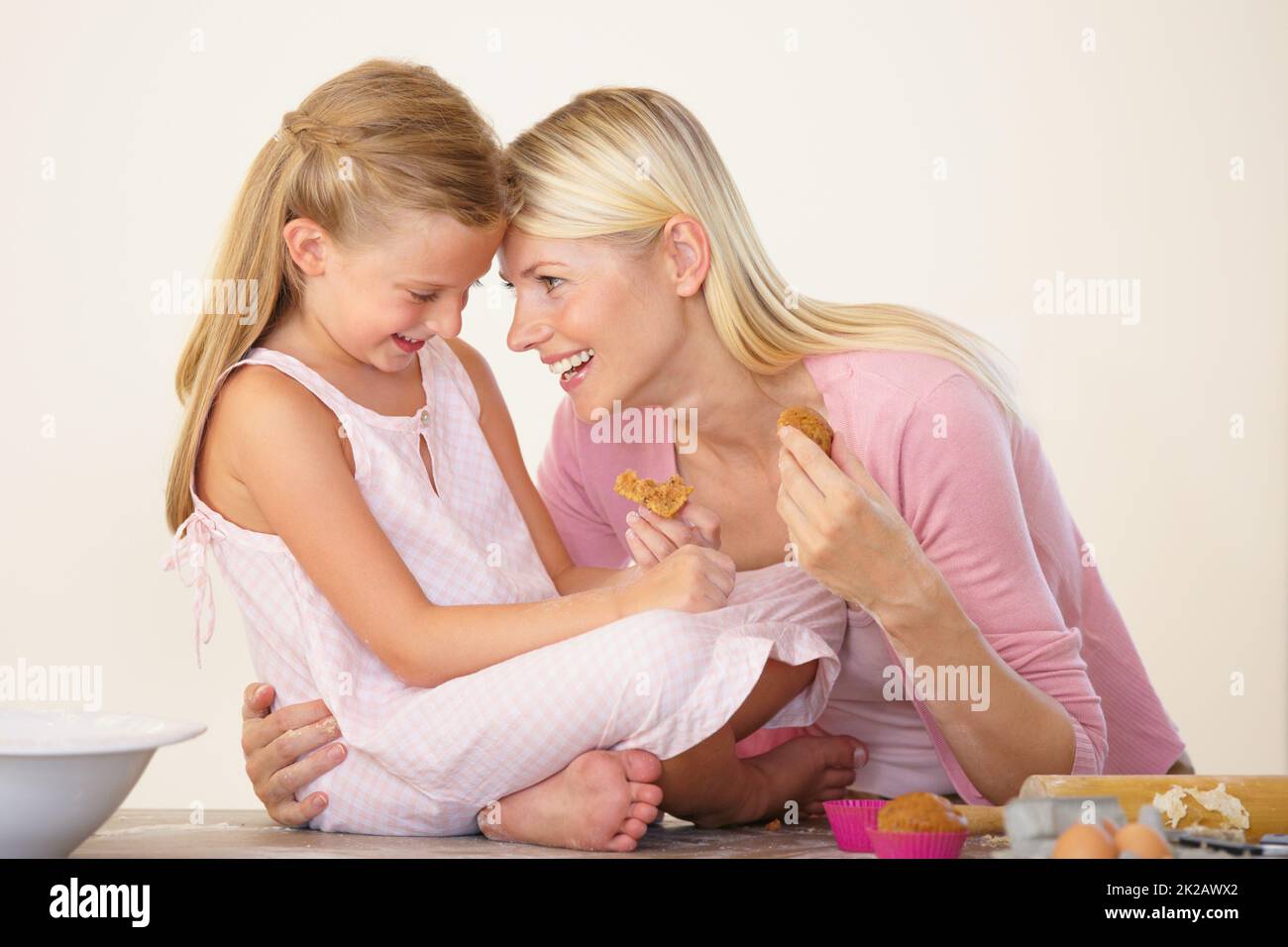 Jeden Moment mit ihr in Ehren halten. Eine Mutter und Tochter essen Muffins nach dem Backen und Kleben. Stockfoto