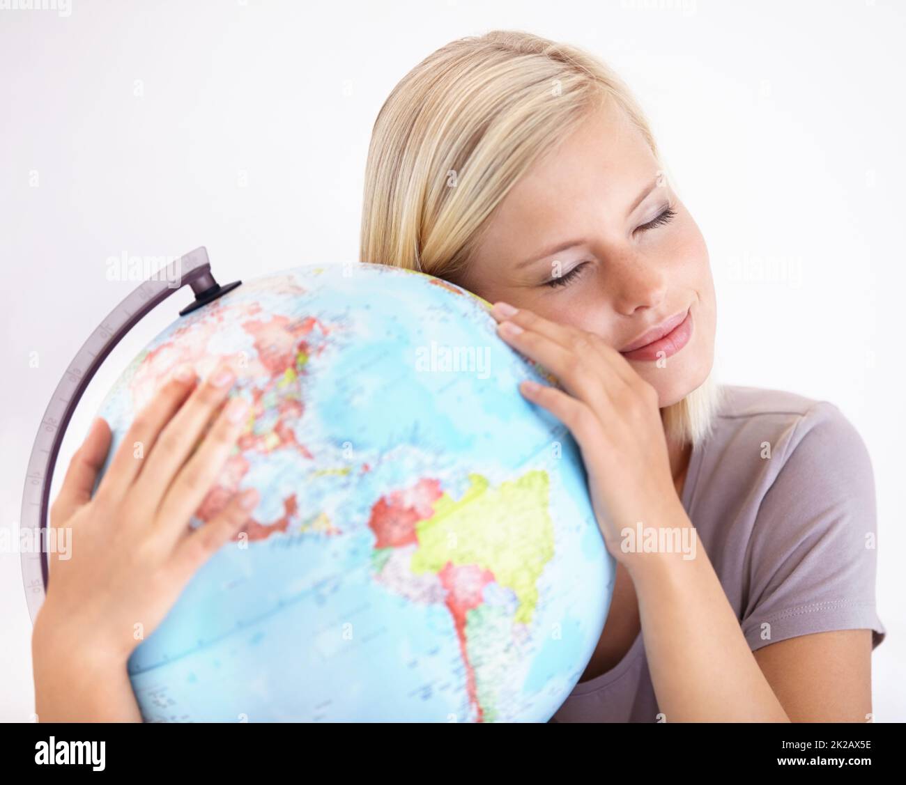 Oh Welt, Ich liebe dich. Eine hübsche junge Frau umarmt liebevoll einen Globus der Erde. Stockfoto