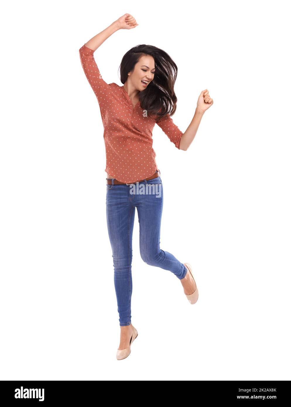 Manchmal musst du dich einfach bewegen. Studioaufnahme einer jungen Frau, die aus Freude auf Weiß springt. Stockfoto
