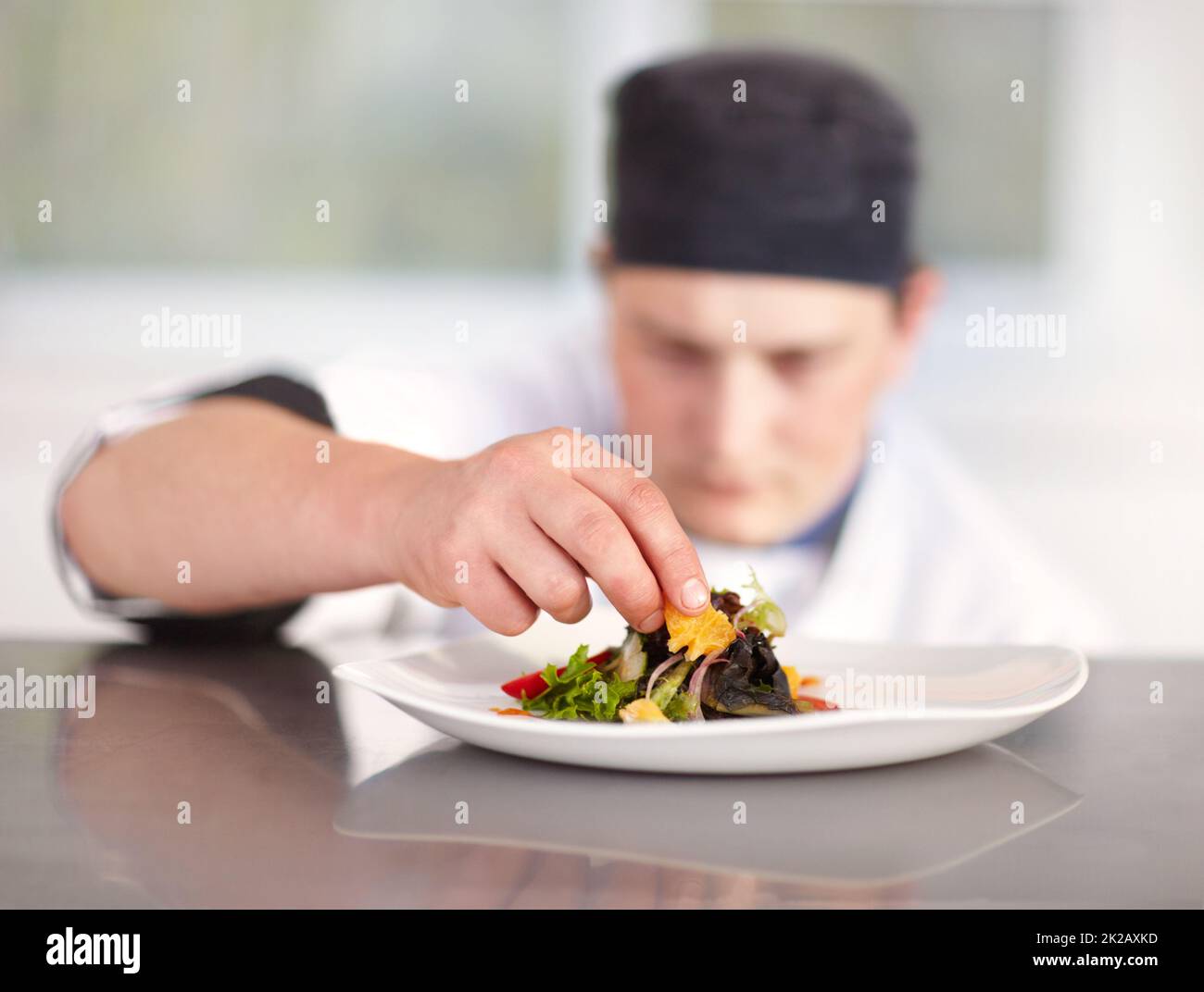 Ich tue alles perfekt. Der junge Küchenchef bringt die letzten Feinheiten zu seinem hervorragend zubereiteten Gericht. Stockfoto