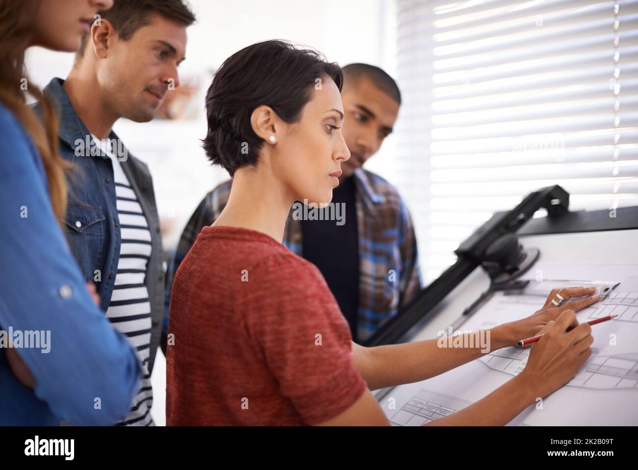 Den Studenten zeigen, wie es funktioniert hat. Aufnahme einer Gruppe junger Designer, die in einem Büro zusammenarbeiten. Stockfoto