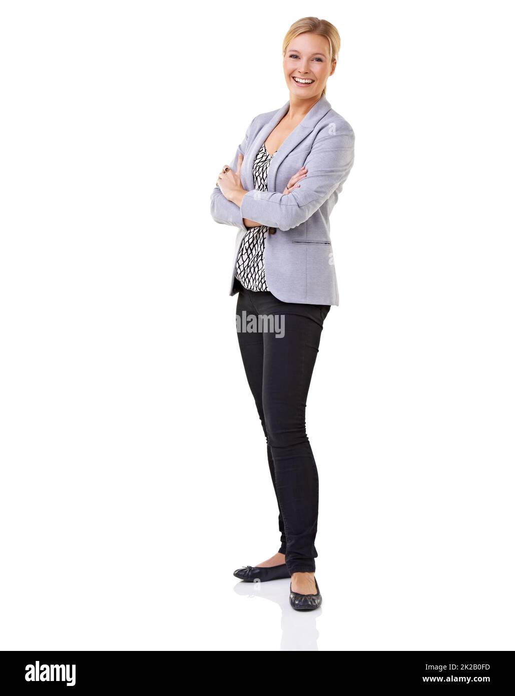 Elegant-legerer Style. Ganzkörperaufnahme einer jungen Frau mit verschränkten Armen isoliert auf Weiß. Stockfoto