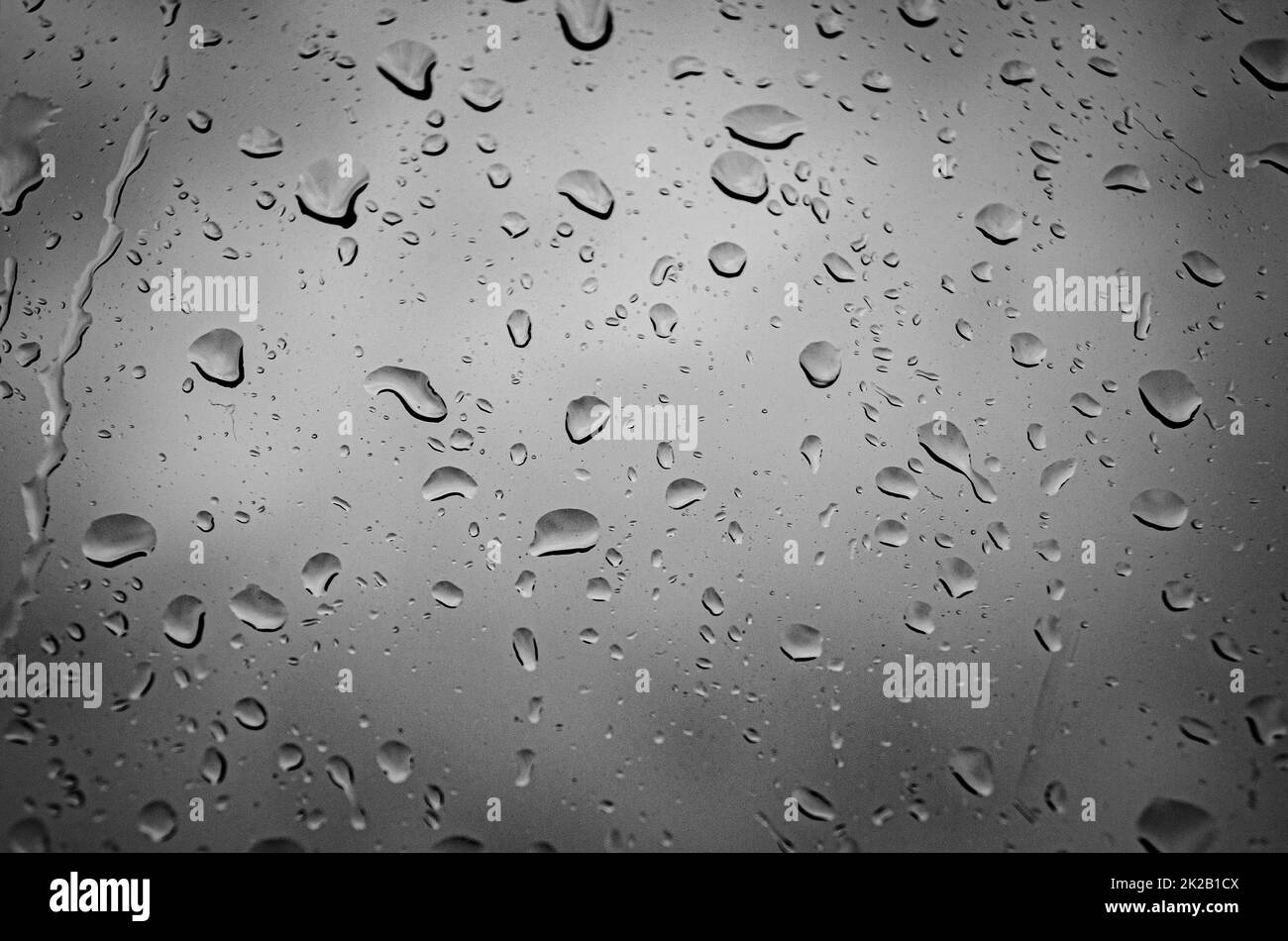 Dunkles Foto von Regentropfen an einem Fenster Stockfoto