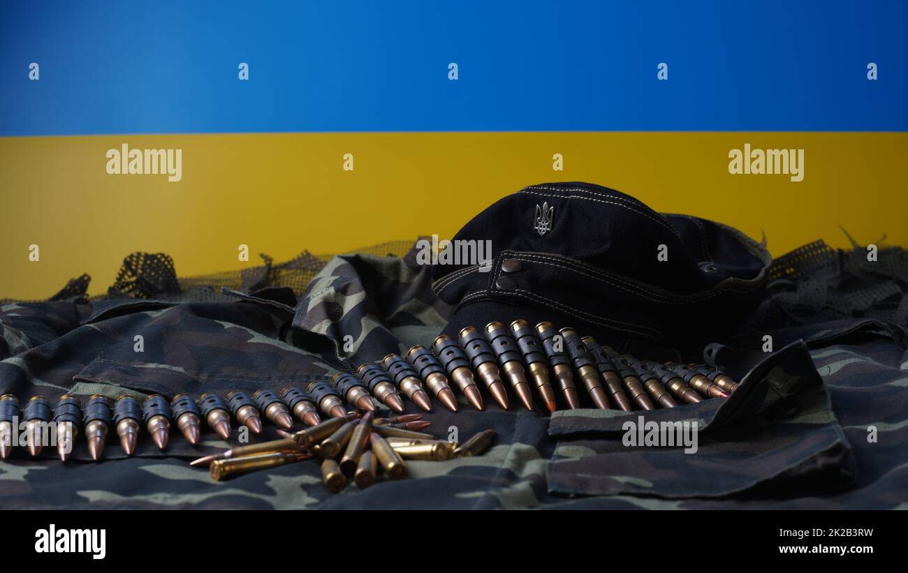 Blau-gelbe Flagge des ukrainischen Nationalsymbols, 5,56mm-Munition, Maschinengewehrkugeln Gürtel, Gewehrmunition in Zeitschriften, ukrainische Uniform und schwarze Militärmütze Stockfoto